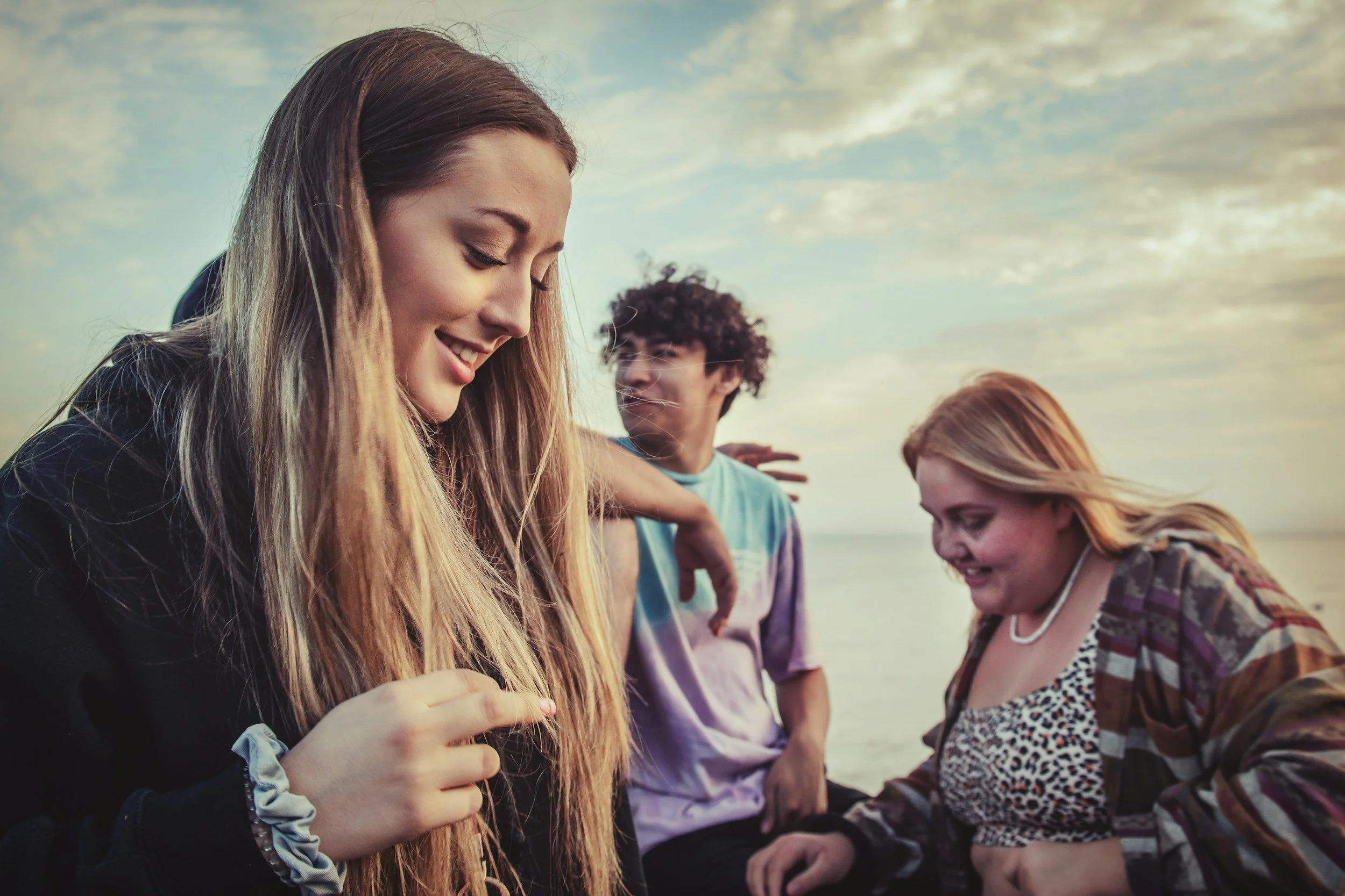 Group of friends laughing together outdoors under a cloudy sky