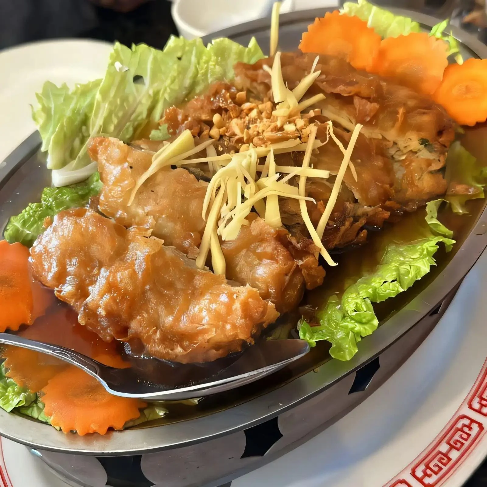 A platter with various sliced vegetables, shredded cheese, and cooked meat, garnished with leafy lettuce and carved tomato slices.