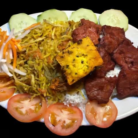 Plate of Indian-style food with cucumber slices, shredded vegetables, yellow rice, grilled paneer, marinated meat, and tomato slices.