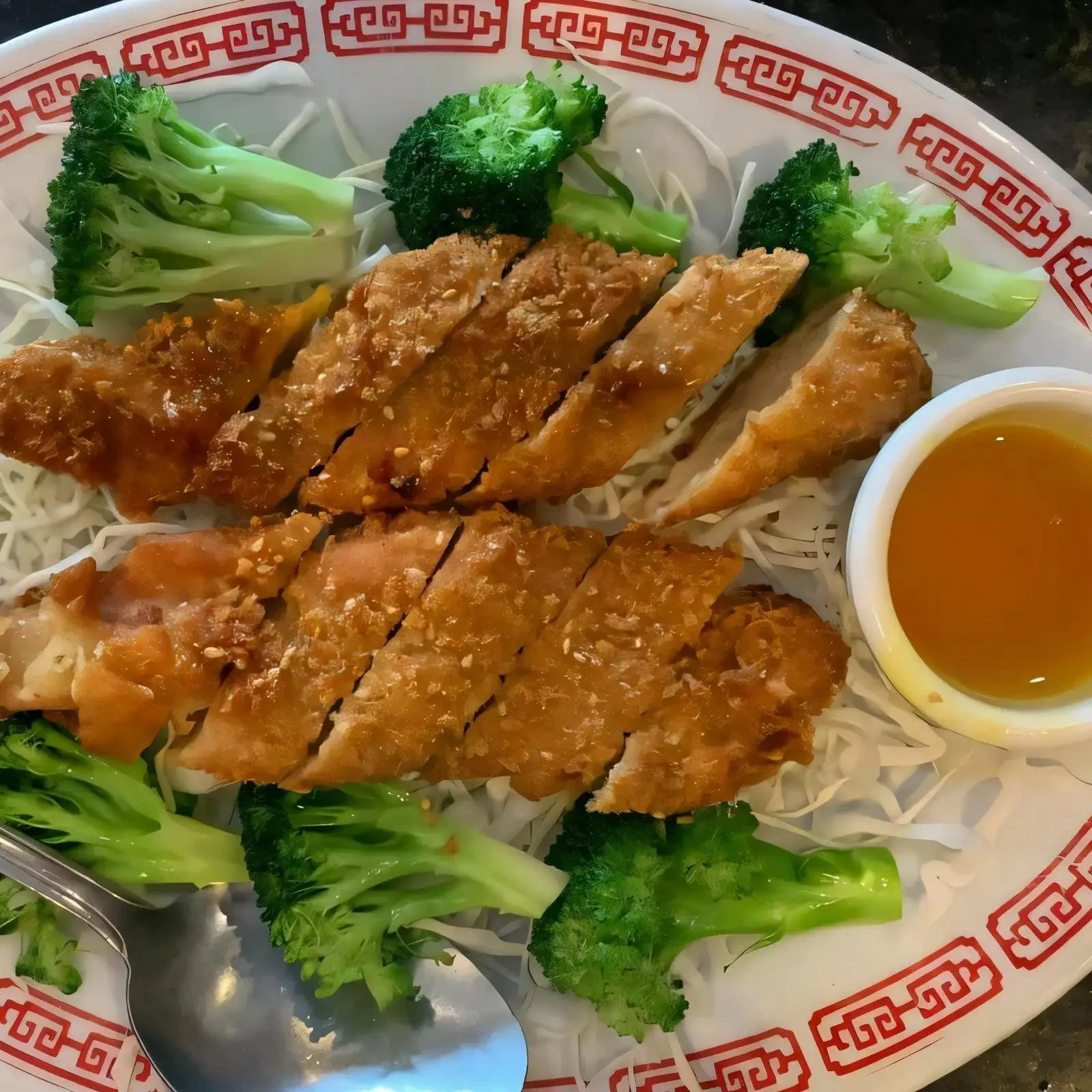 Plate of crispy fried spring rolls served with fresh broccoli and a small bowl of dipping sauce.