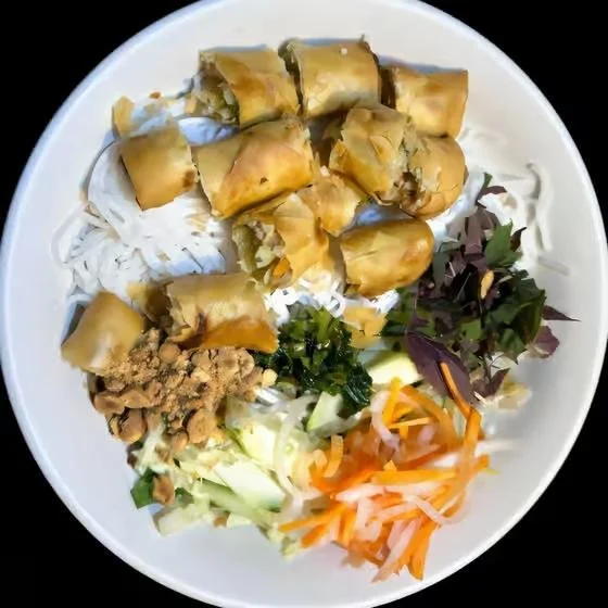 Bowl of Vietnamese spring rolls with rice noodles, fresh vegetables, and herbs.
