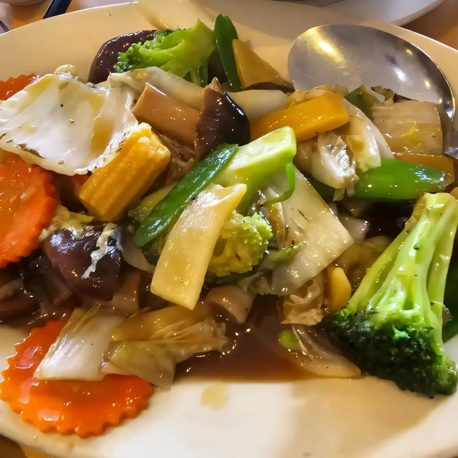 A bowl of assorted steamed vegetables including broccoli, carrots, cabbage, zucchini, and various mushrooms.