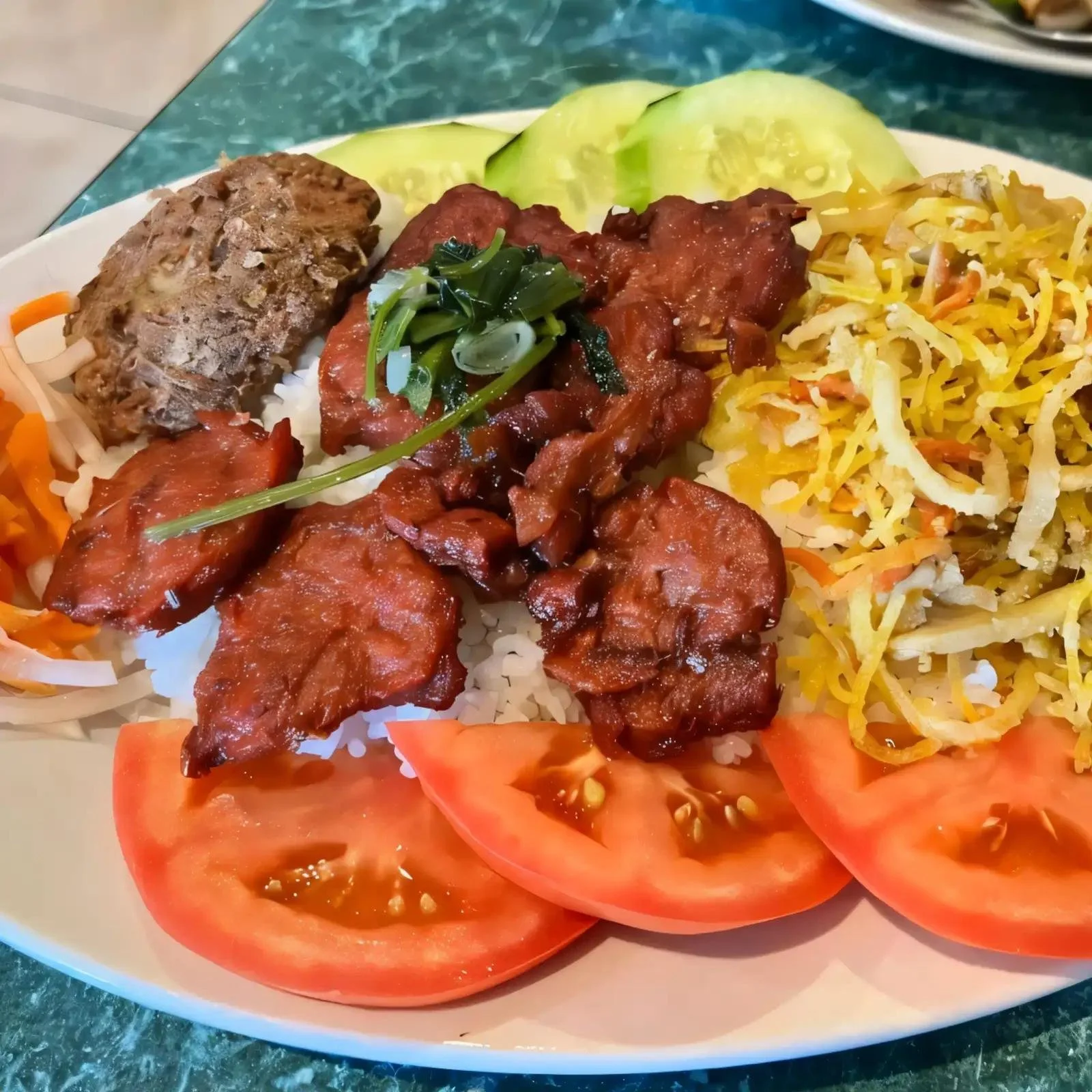 A plate of fresh vegetables and meats, including sliced tomatoes, shredded cabbage, cooked meat, and tomato slices, served on a white dish.