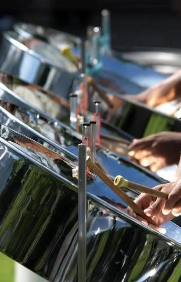 Close-up of hands playing steel drums at an outdoor event.