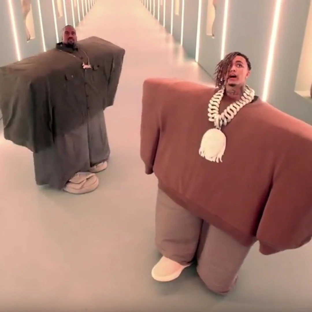 Two people dressed in oversized, inflatable costumes resembling characters from the animated series 'Rick and Morty' walking down a brightly lit corridor.