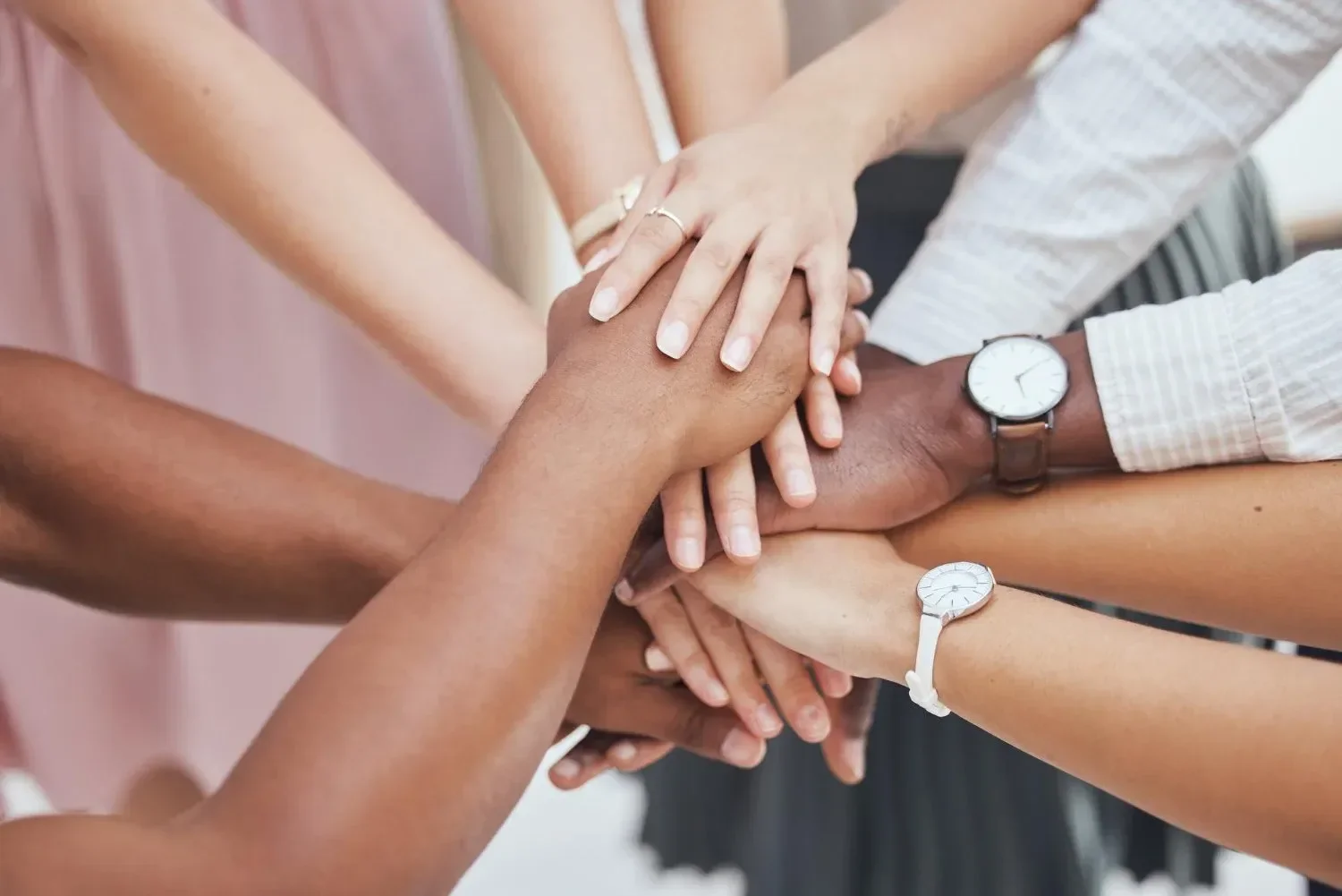 People placing their hands on top of each other in a group gesture, showing teamwork and unity.