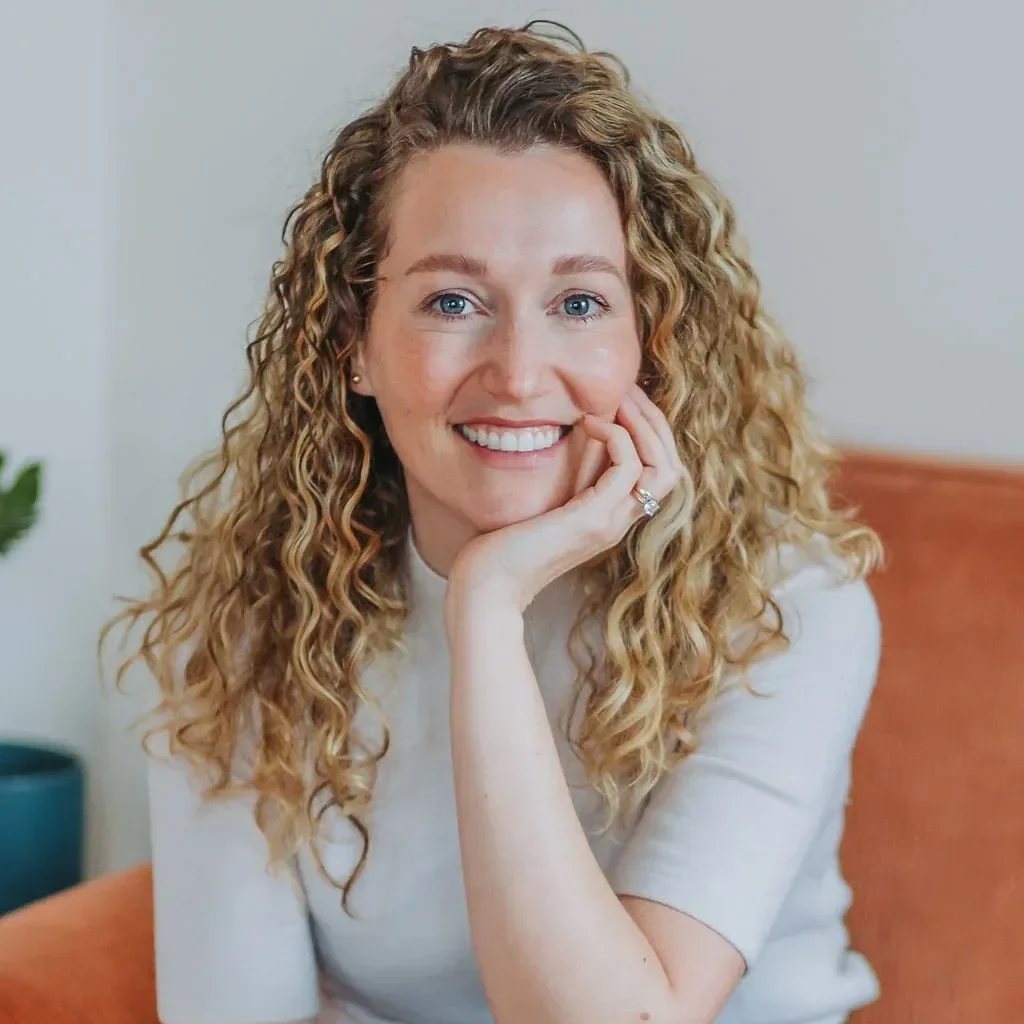 Dr. Angela Koenig with long curly blonde hair resting her hand on her cheek