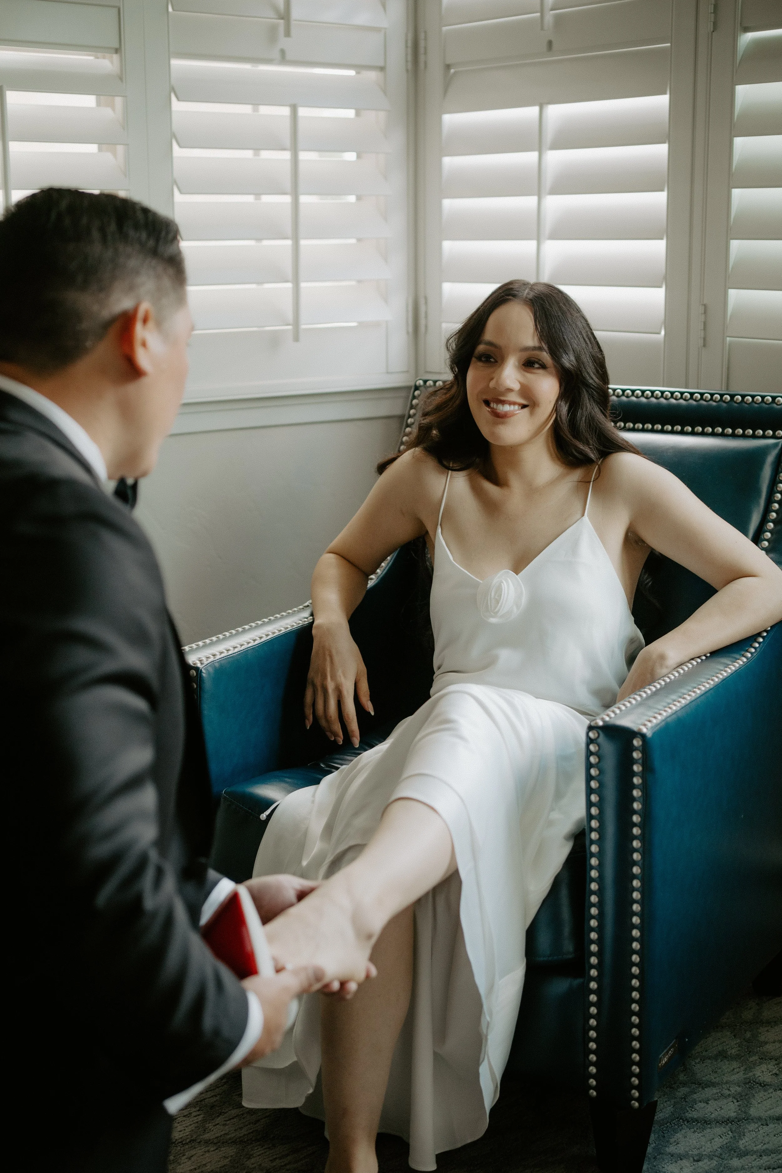 Groom placing a show on his brides foot as they smile into each others eyes.