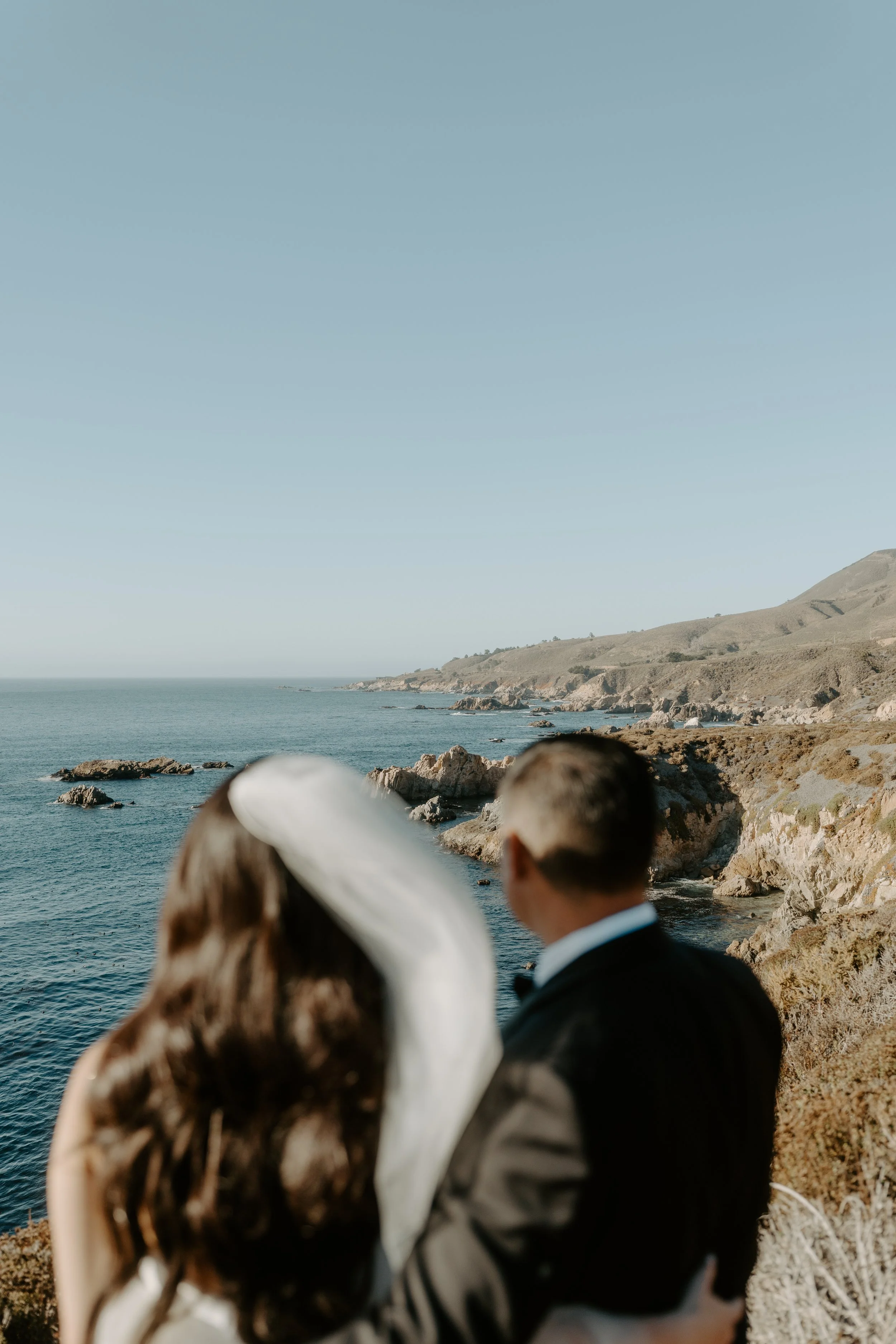 Couple staring into the pacific ocean on the big sur coast.