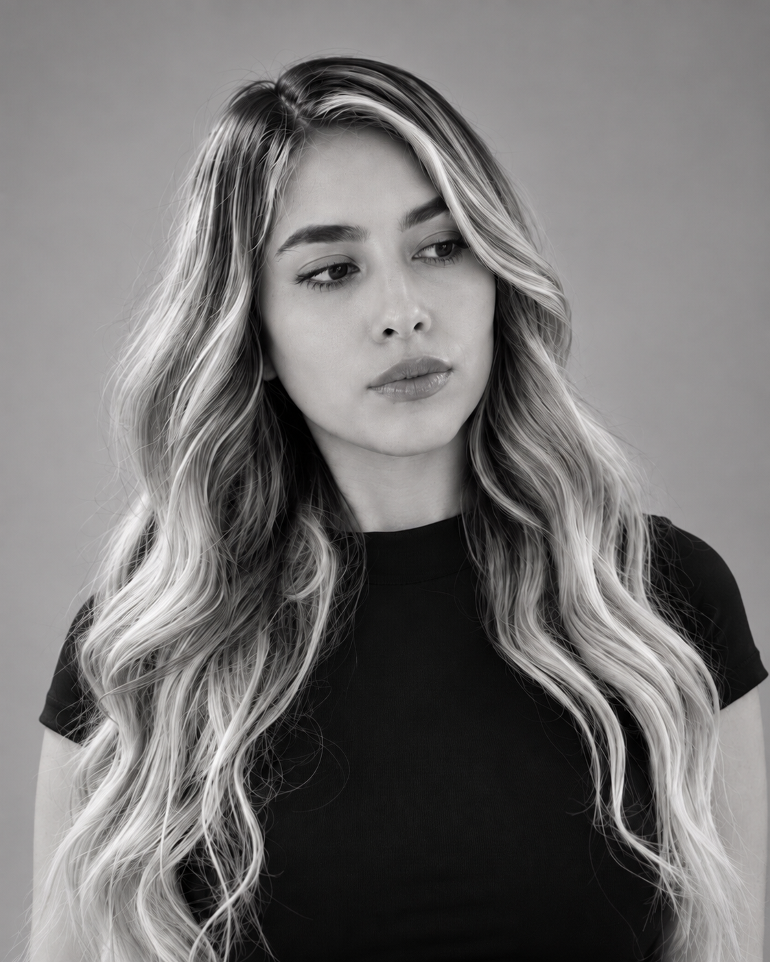 Black and white portrait of a young woman with long, wavy hair, wearing a black top, looking slightly to the side.