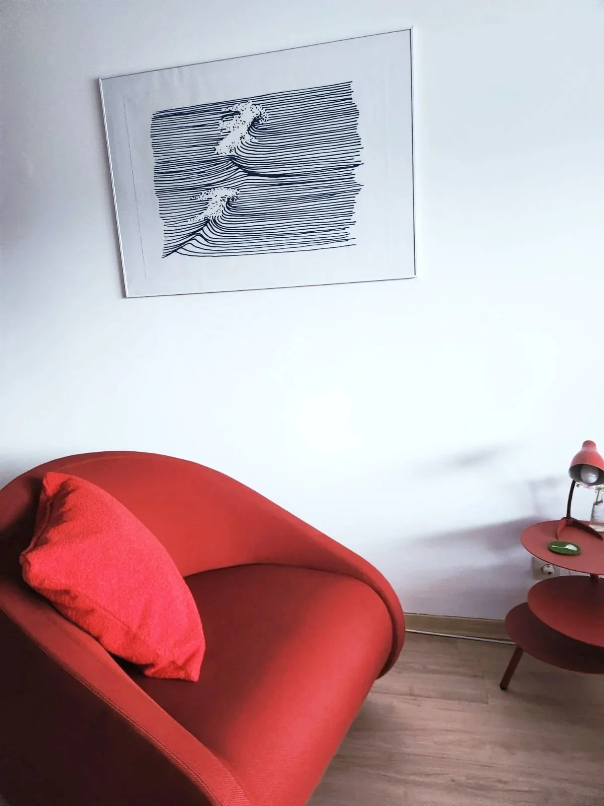 Modernes rotes Sofa mit Kissen, Beistelltischen und abstrakter Linienkunst an einer weißen Wand