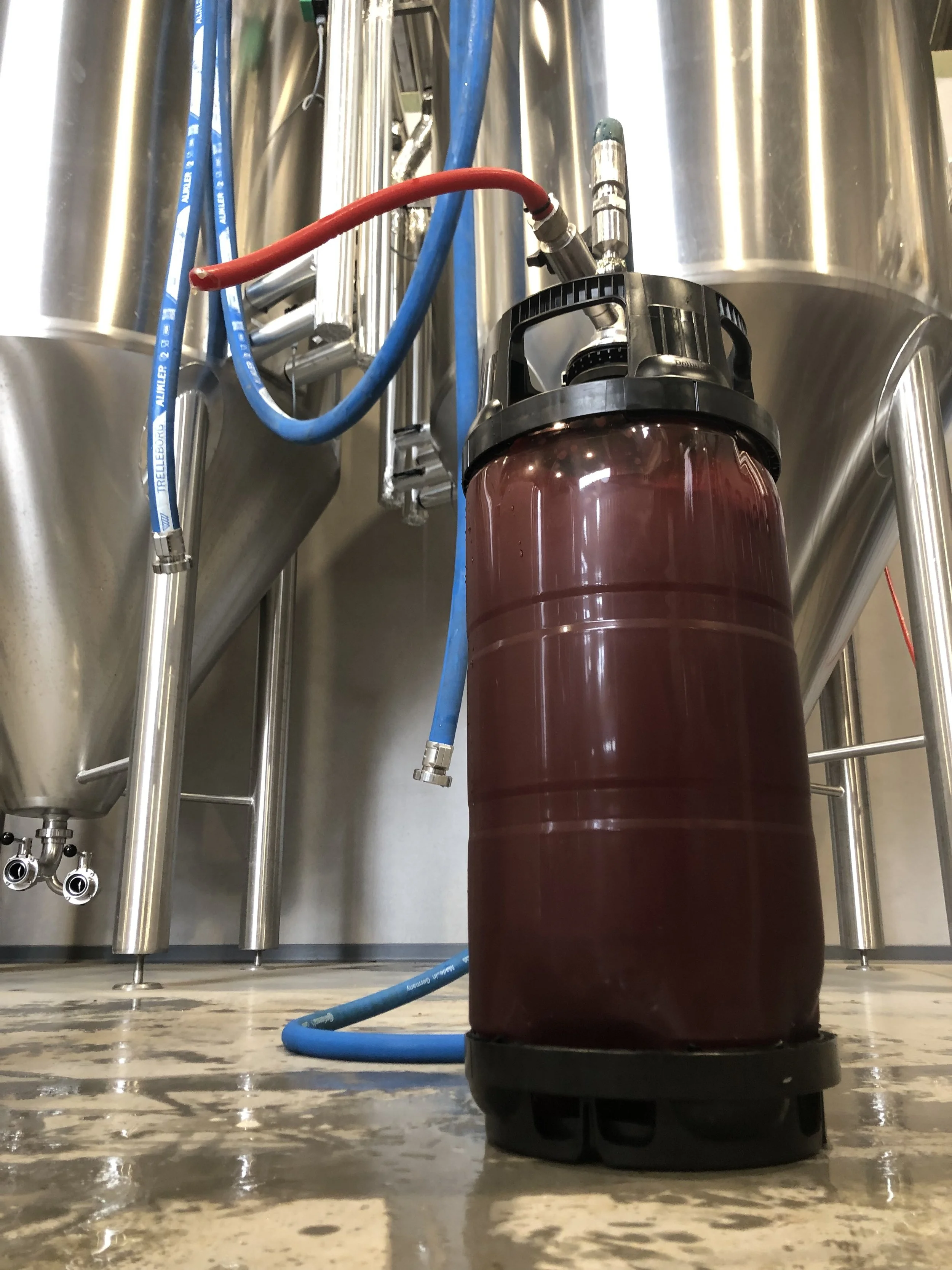 Een vaten met een kleurige inhoud in een industrieel vat met pijpen en slangen.