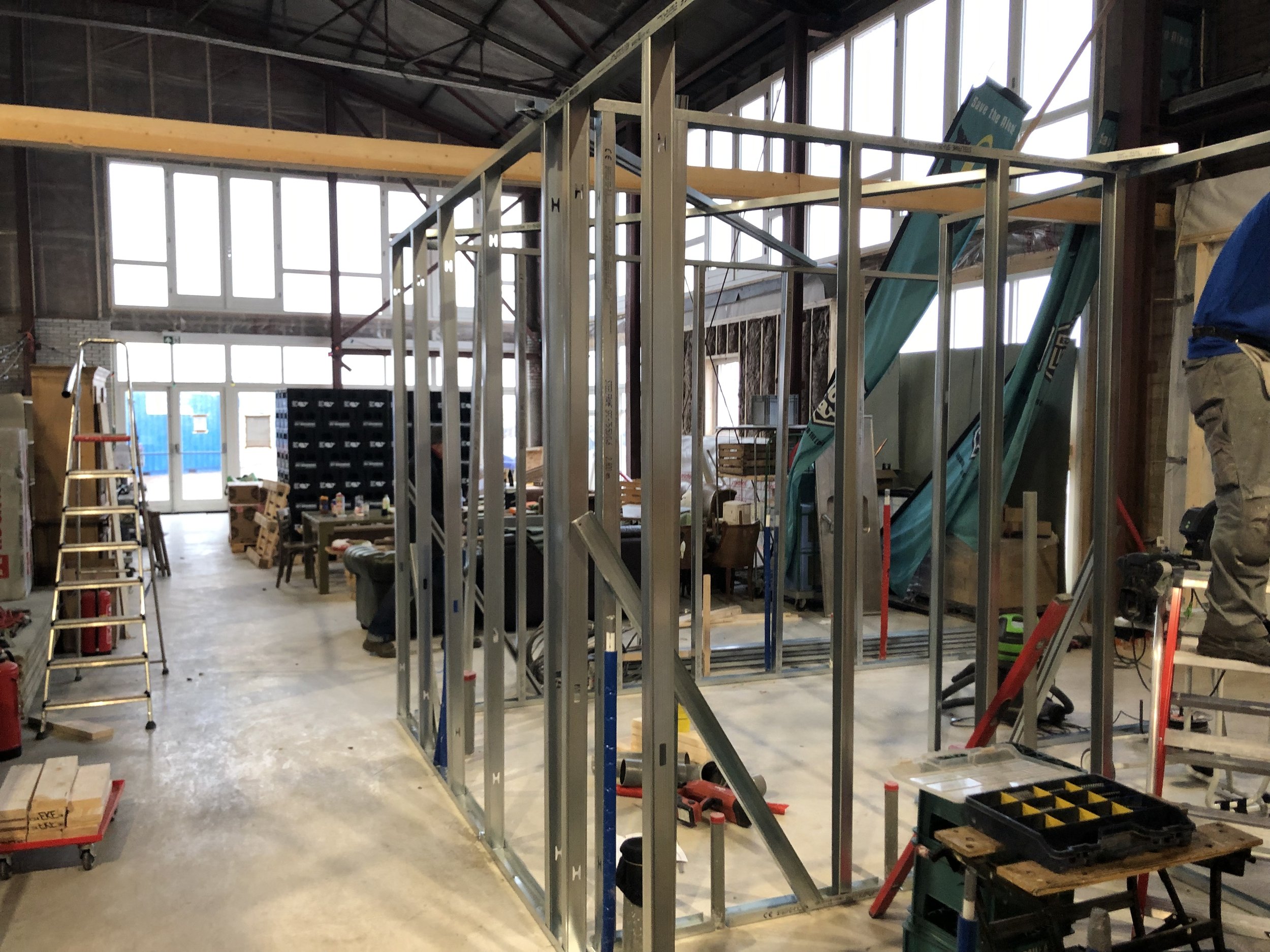 Binnen in een bouwplaats met metalen frame constructie, ladders, bouwmaterialen en gereedschappen.