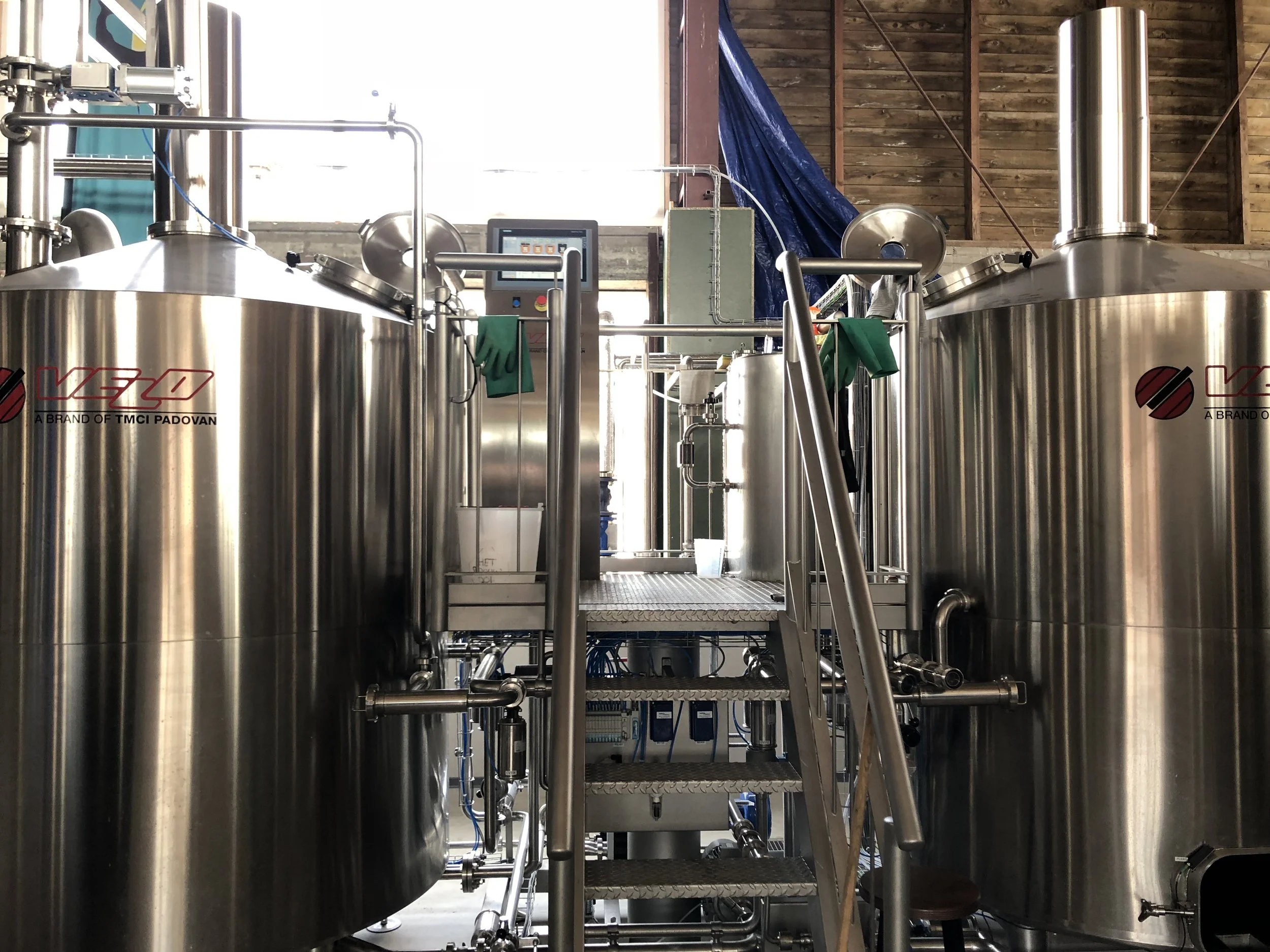 Roestvrijstalen tanks en piping in een industriële brouwerij, mogelijk voor de productie van bier of andere dranken.