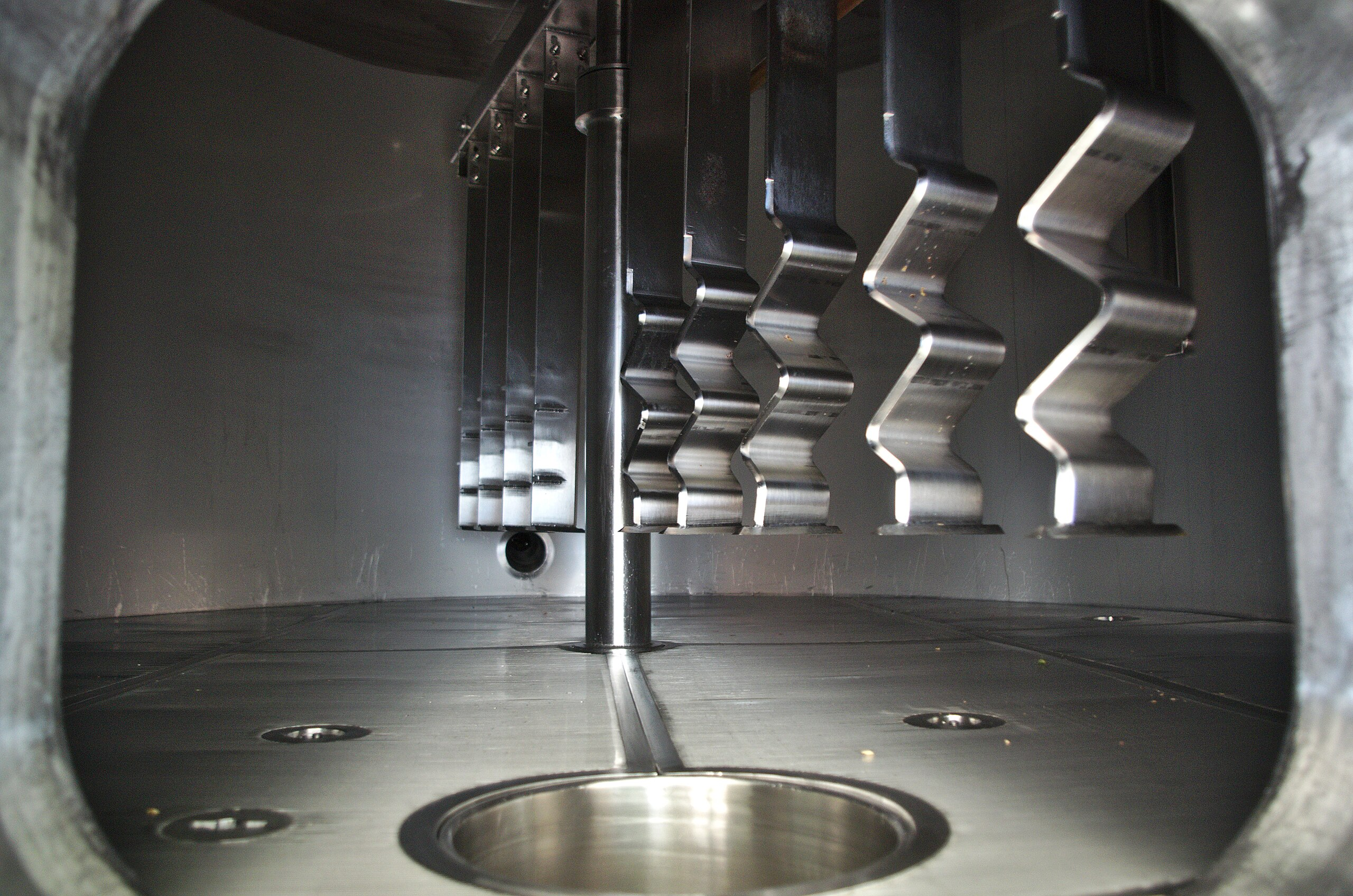 Binnenkant van een industriële machine met metalen tandwielen en schroef, gezien door een opening.
