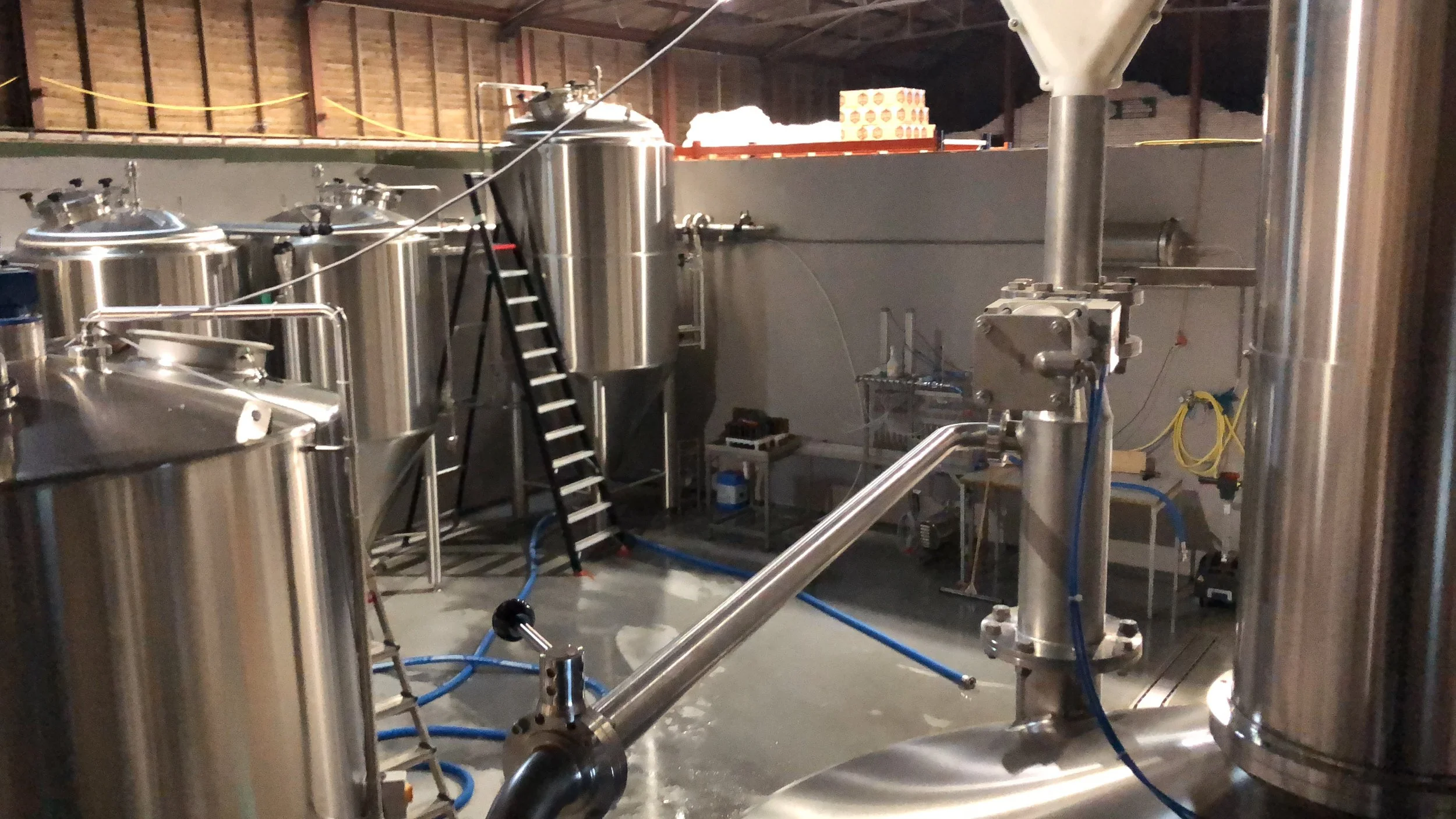 Industrieel installatie met metalen tanks, leidingen en een ladder in een fabriek of laboratorium.