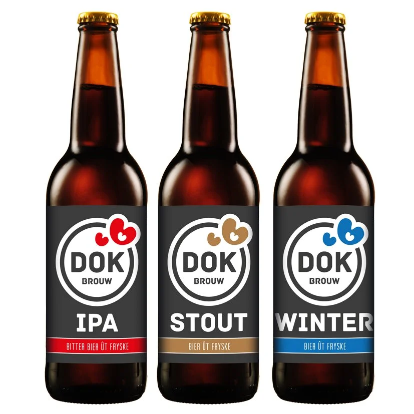 Drie flesjes met verschillende soorten bier: IPA, Stout en Winter, allemaal van het merk DOK Brouw, met zwarte etiketten en gekleurde deksels en details.
