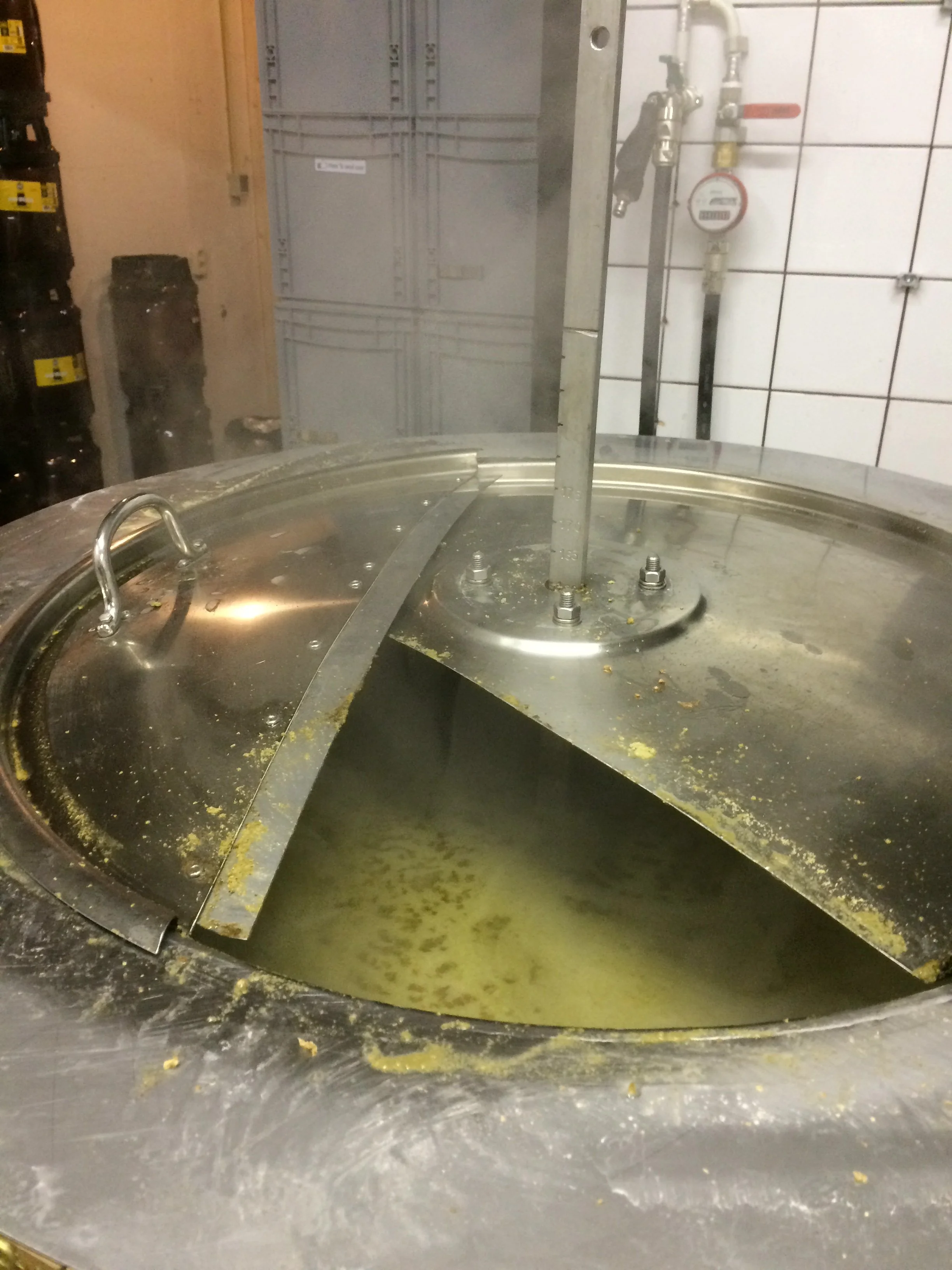 Een industriële keuken of horecagelegenheid met vuile, vetgeregende oppervlakken en een grote pan met gele inhoud, mogelijk oliebestendig of vetafstotend. 