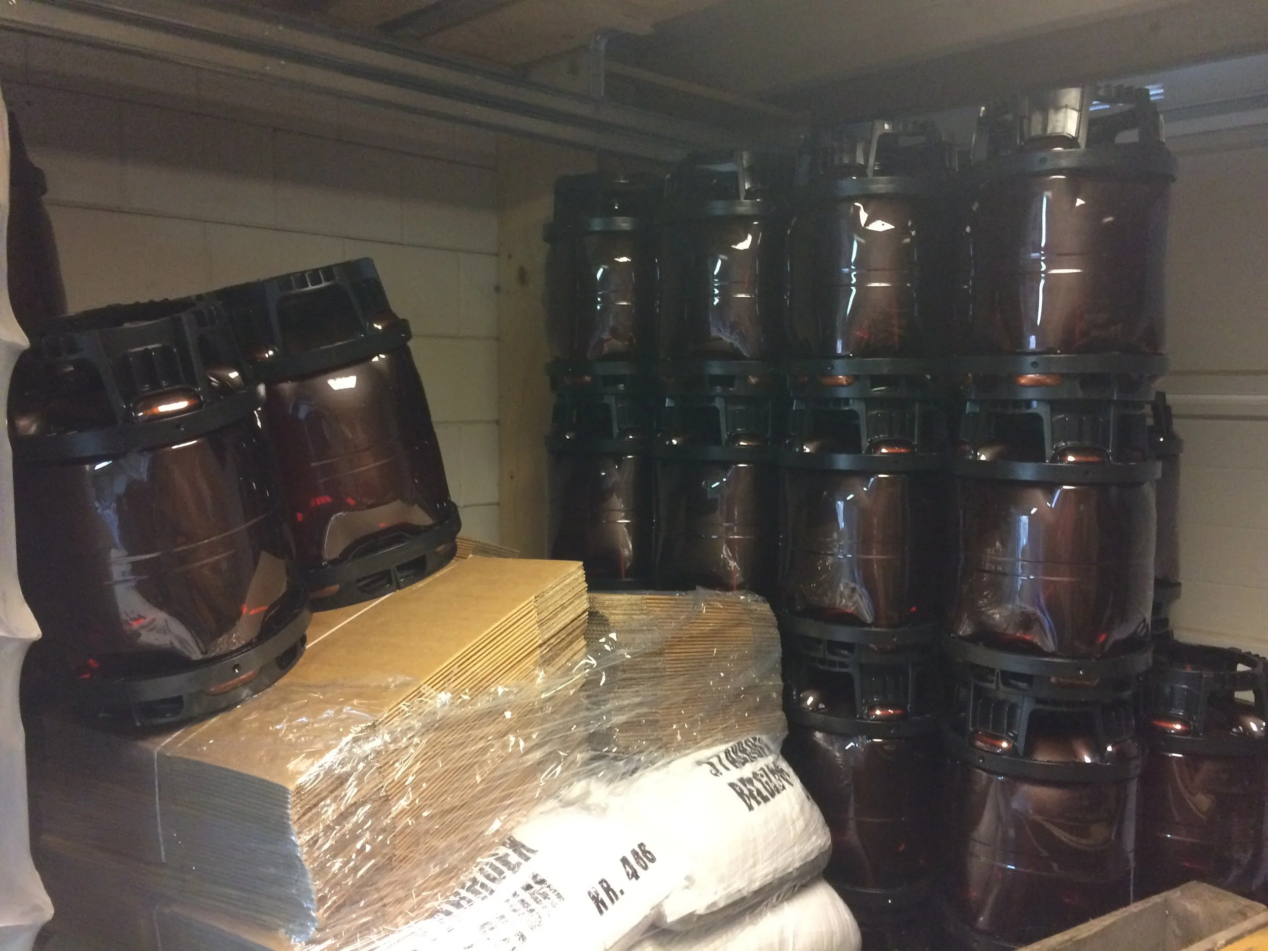 Rijen met bruine plastic containers en kartonnen platen, verpakt in plasticfolie op een houten pallet.