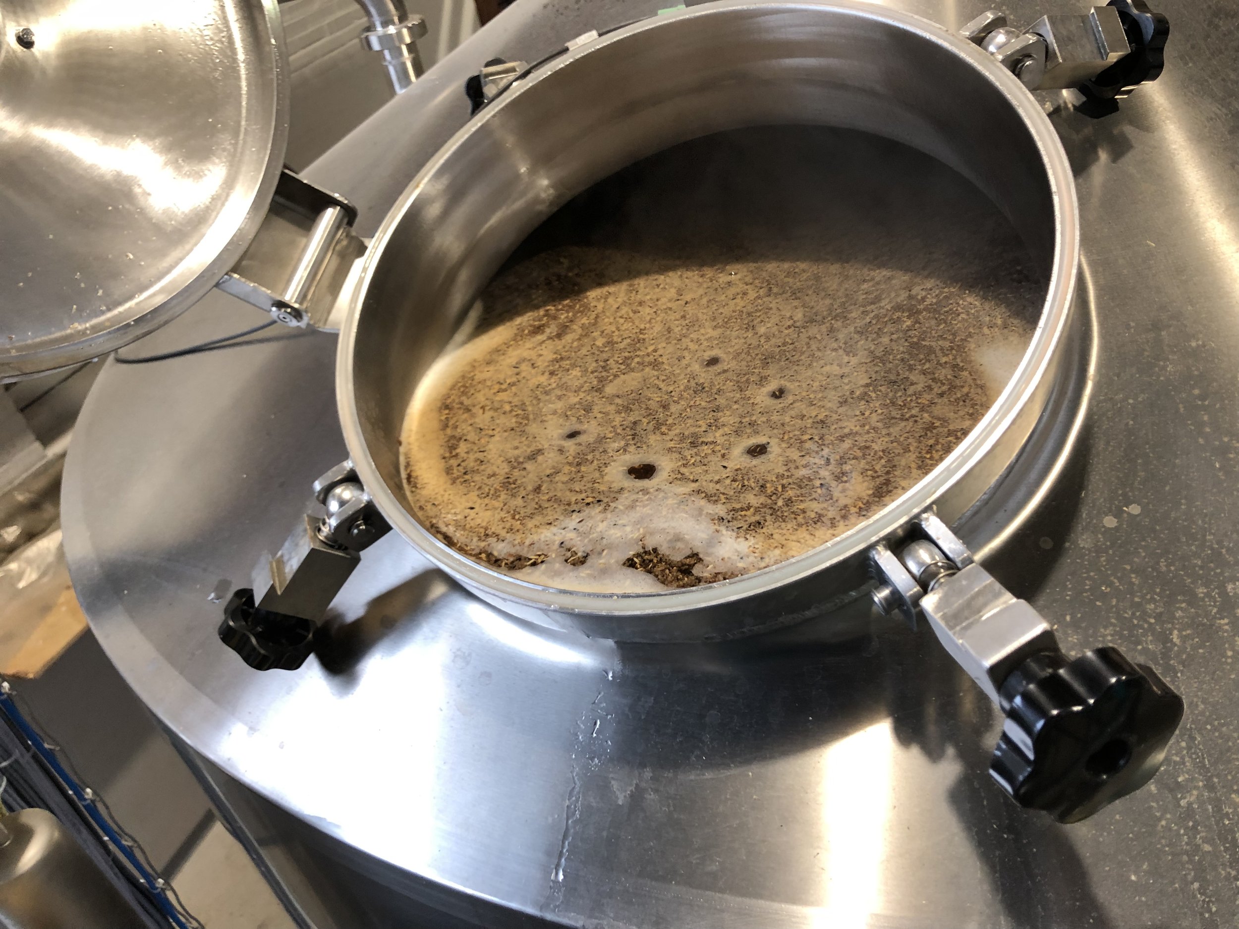 Een roestvrij stalen koffiepot met overloop, waarin koffiedik zichtbaar is.