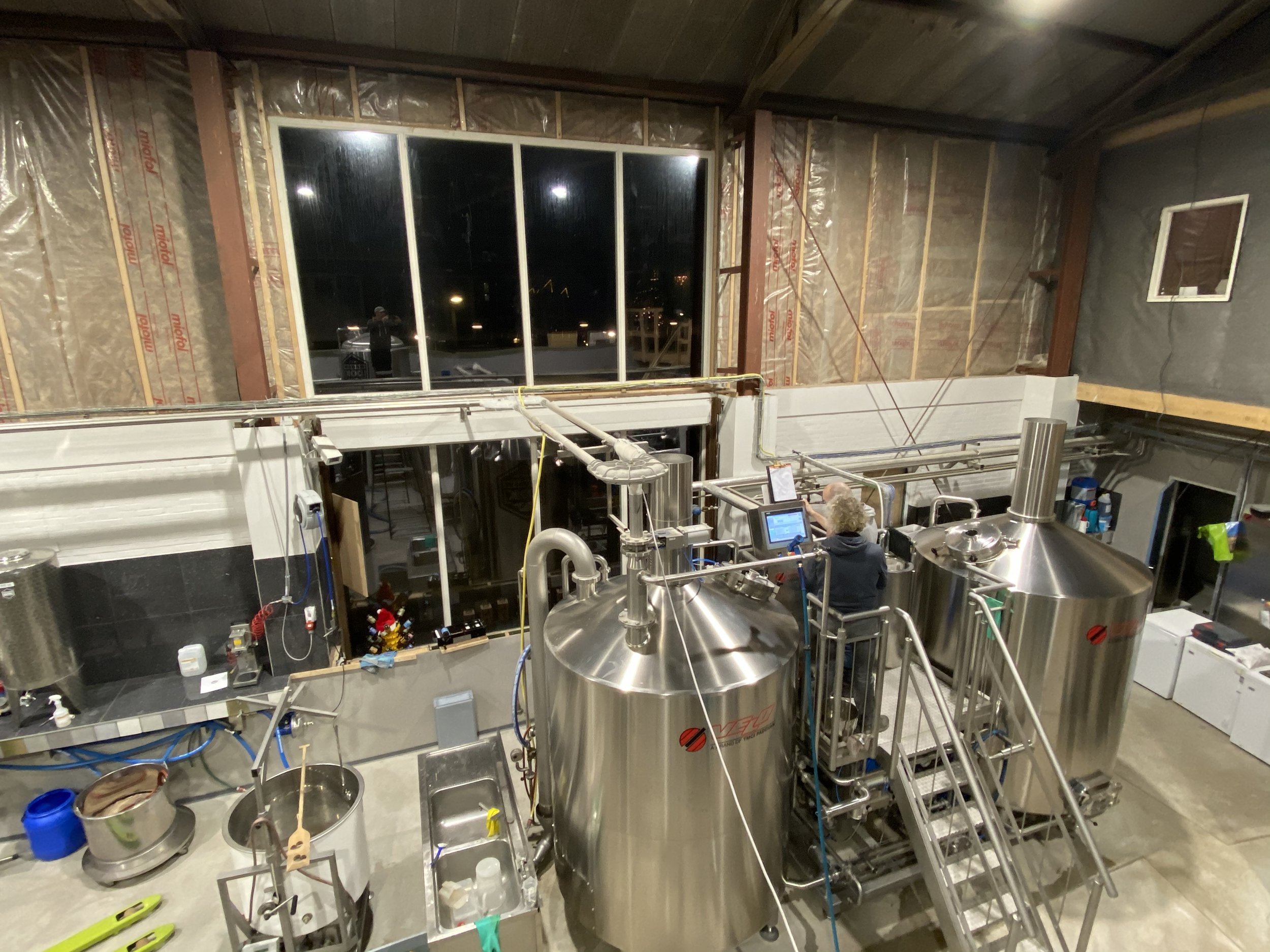Interne bouw van een industrieel of commercieel pand, met raam en diverse technische installaties en apparatuur in opbouw.