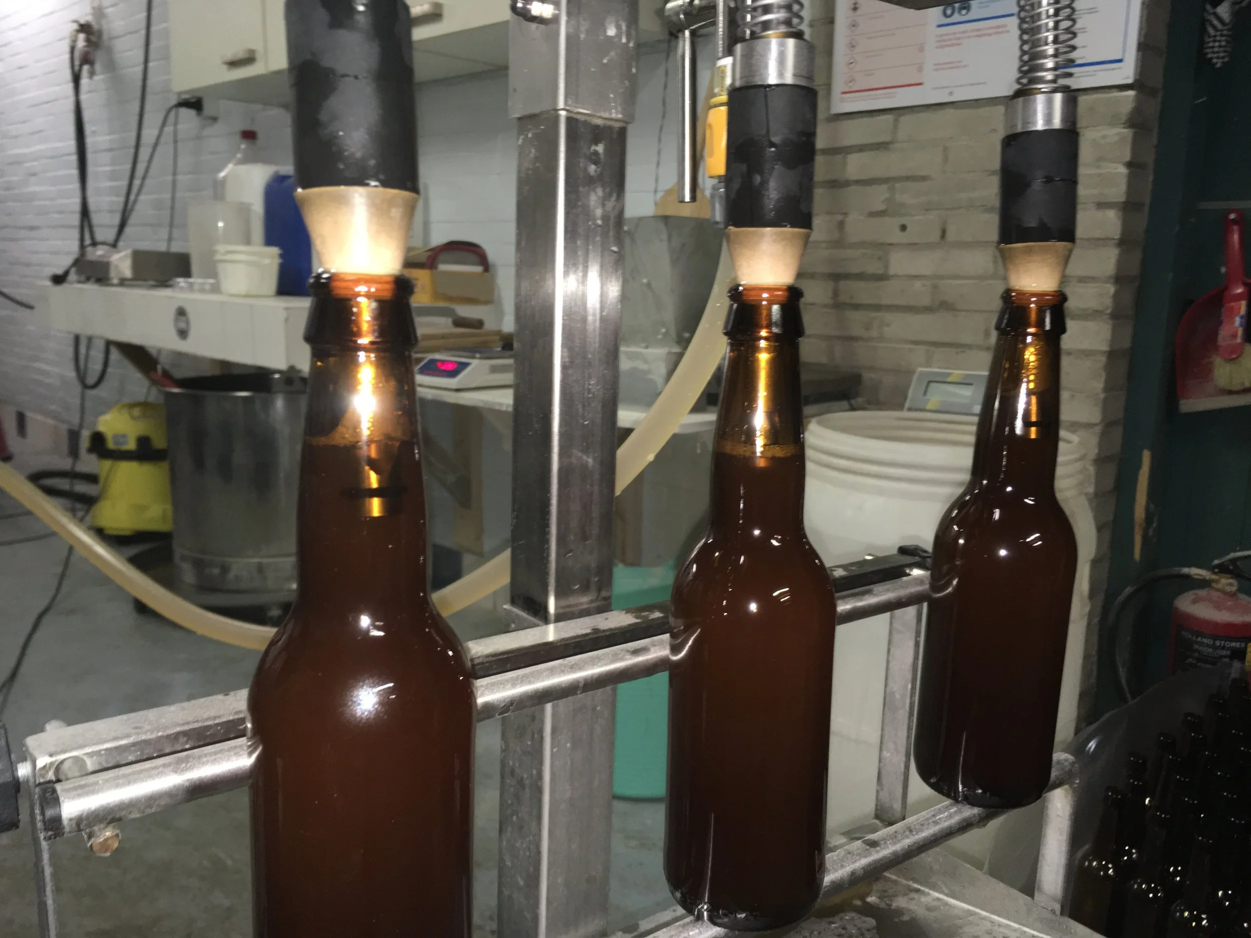 Flessen met bier die door een automatische bottelmachine worden gevuld.