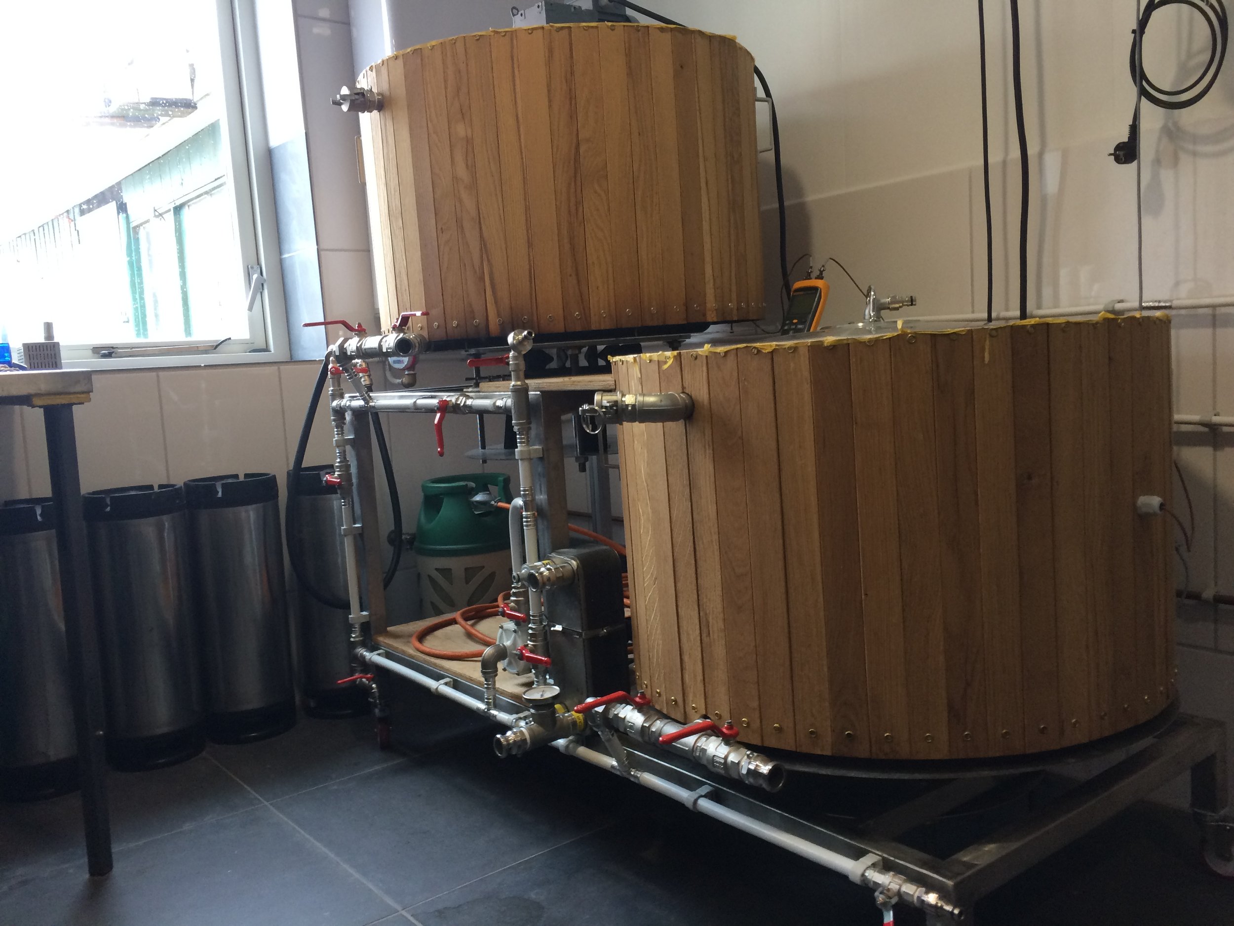 Een machine of opstelling met houten delen, metalen buizen, ventielen, leidingen en instrumenten in een binnenomgeving, mogelijk een laboratorium of technische werkplaats.