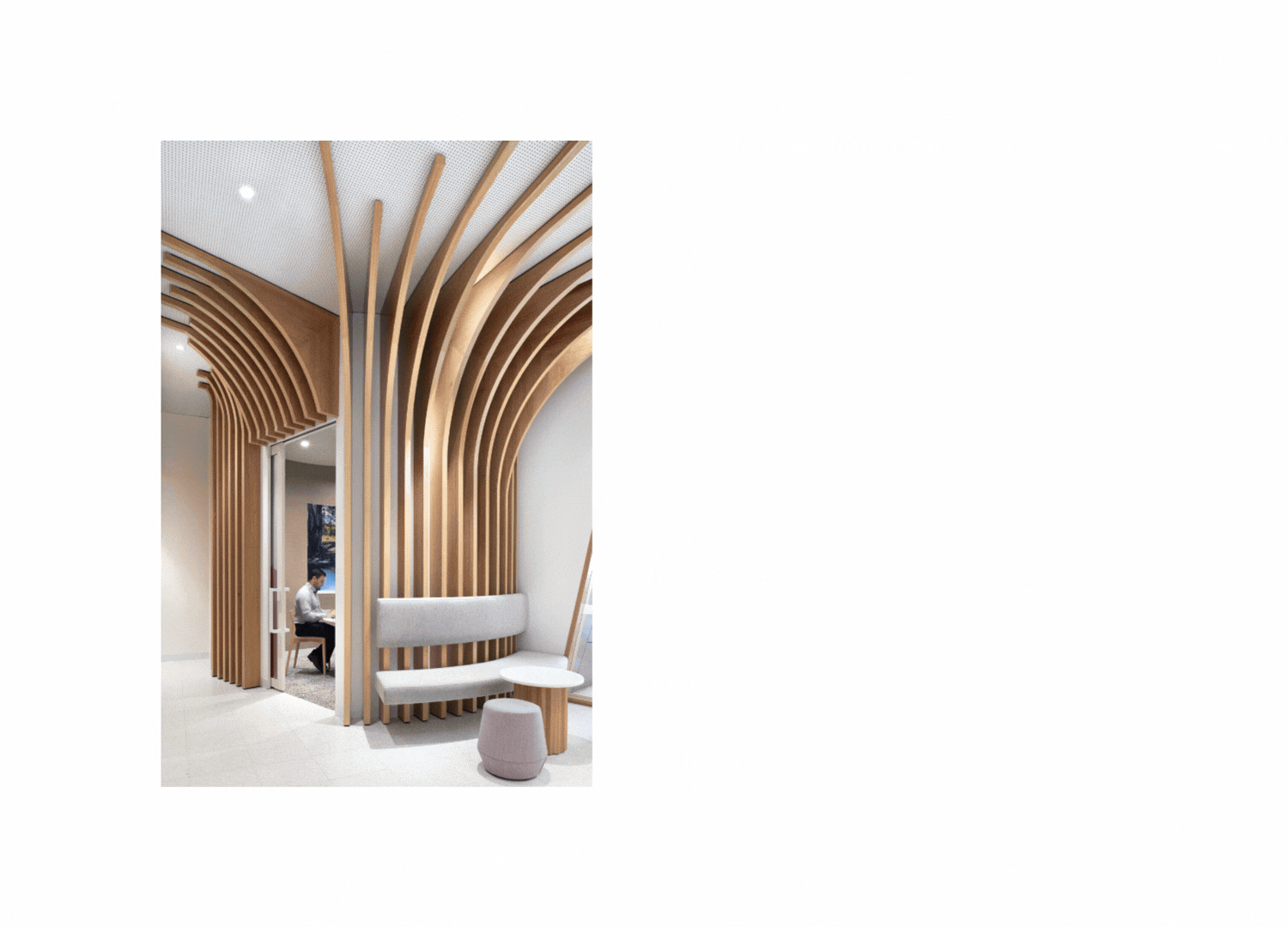 Modern interior design with wooden architectural arches, a person sitting at a desk, and a cozy seating area with a bench and ottoman.