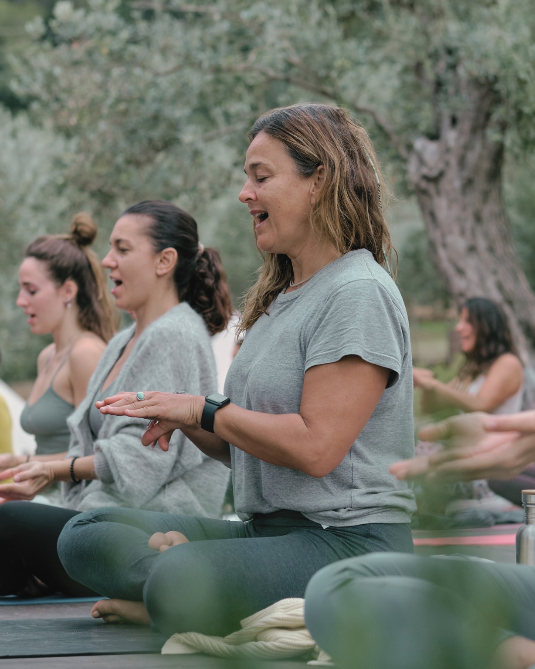 Menschen, die an einer Yoga- oder Meditationssitzung im Freien in einem Park oder Wald teilnehmen.