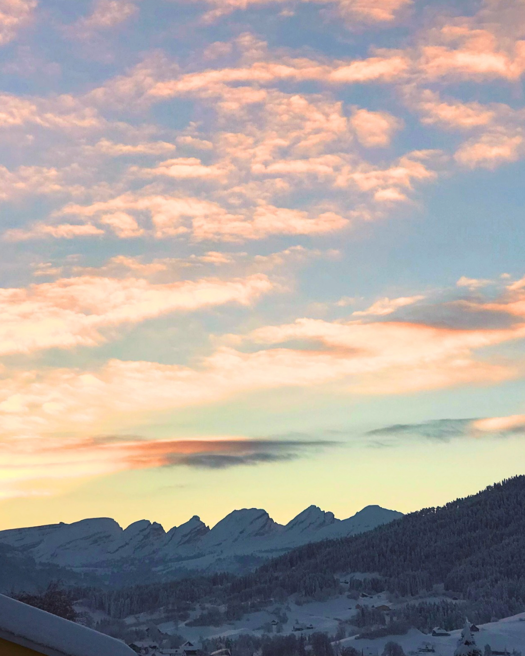 Die Churfirsten Berge unter einem Himmel mit bunten Wolken beim Sonnenuntergang.