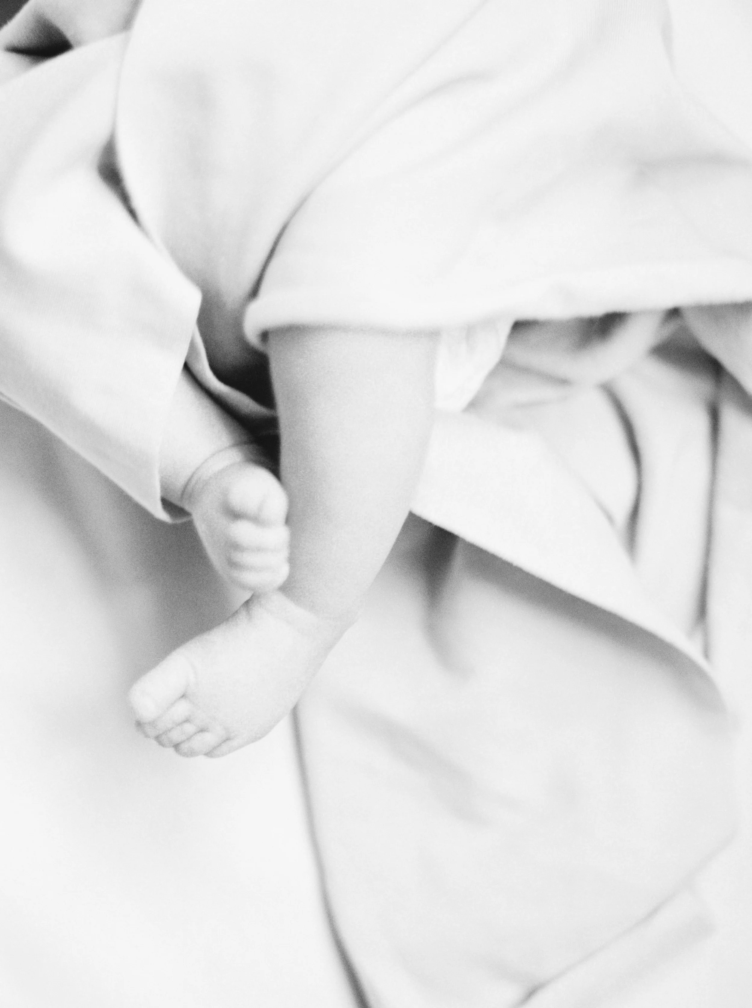 Close-up black-and-white photo of a person holding a baby's foot at a Dartmouth family session. 