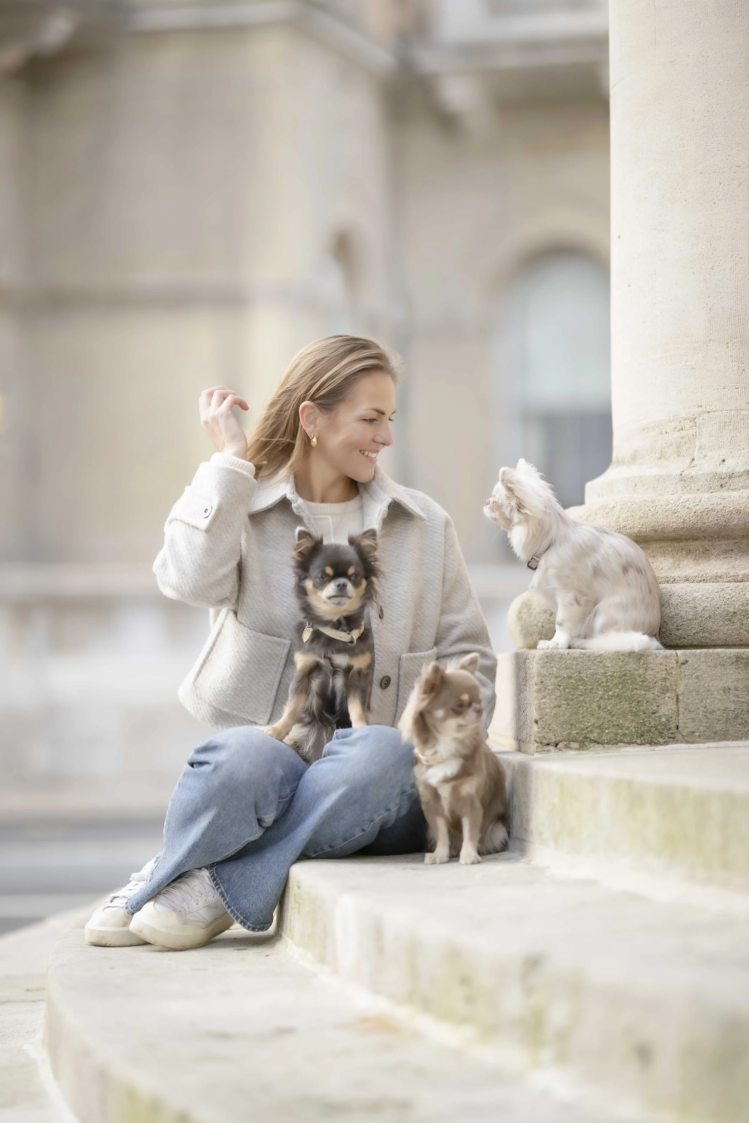 Lilo Ask-Henriksen sitting on stone steps with her four small dogs