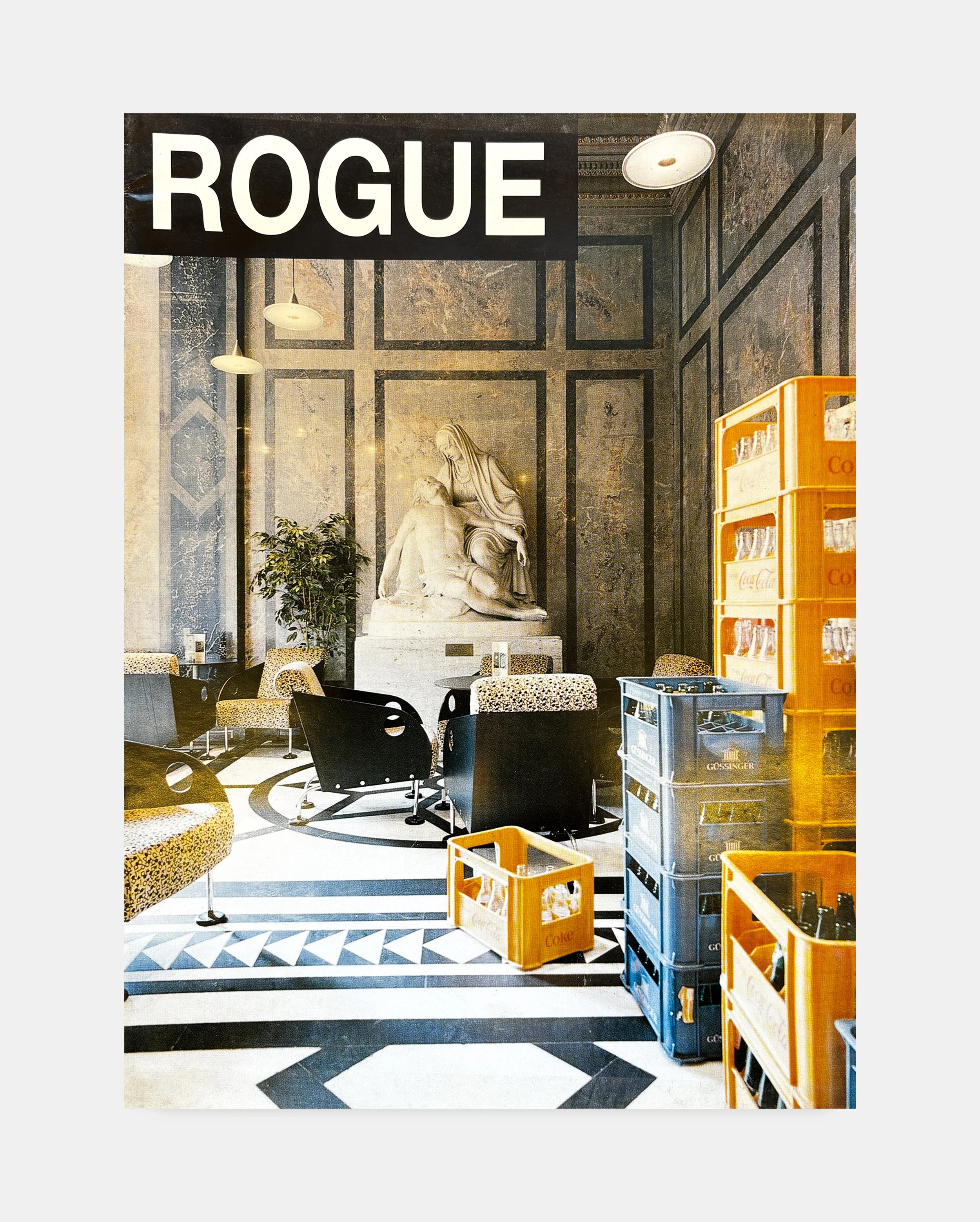 Interior of a cafe or restaurant with a large sign that says 'ROGUE' hanging from the ceiling, marble walls with black trim, a statue of Mary holding baby Jesus, and tables surrounded by leopard print chairs. Several crates of bottles and glasses are