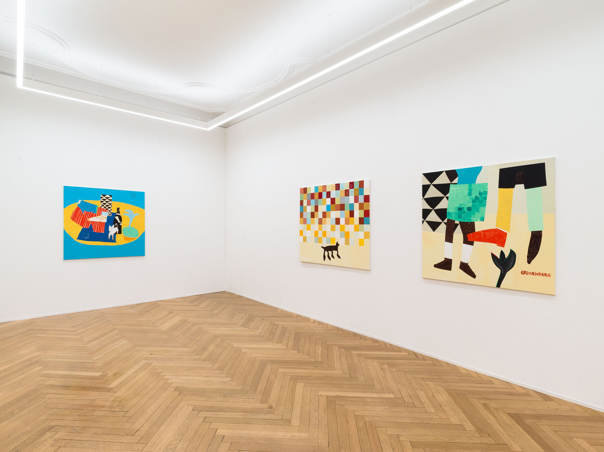 Gallery wall with colorful abstract paintings in a white-walled art gallery with wooden floors.