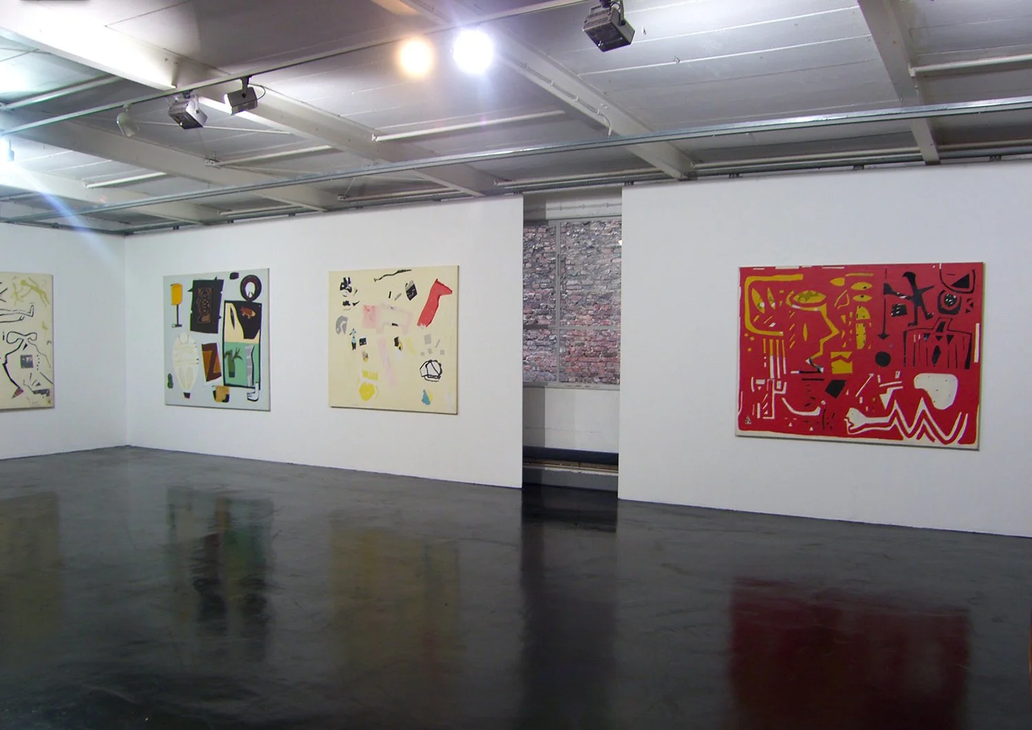 An art gallery with white walls displaying four abstract paintings. The gallery has a wooden floor and ceiling mounted spotlights.