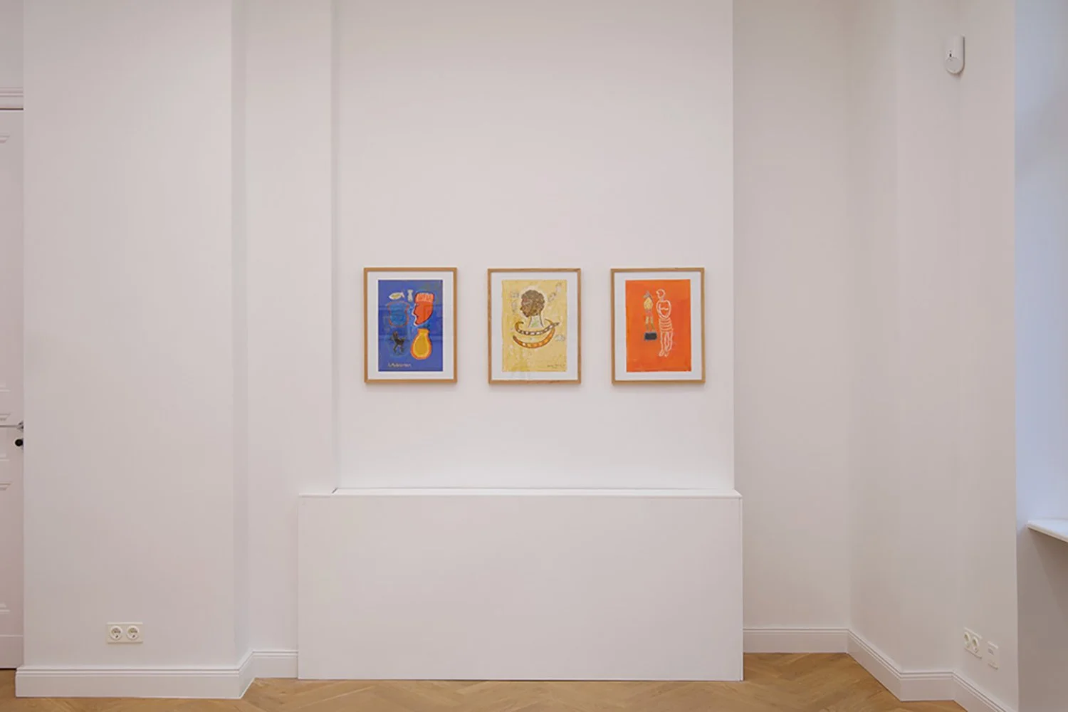 Three framed colorful abstract artworks on a white gallery wall.
