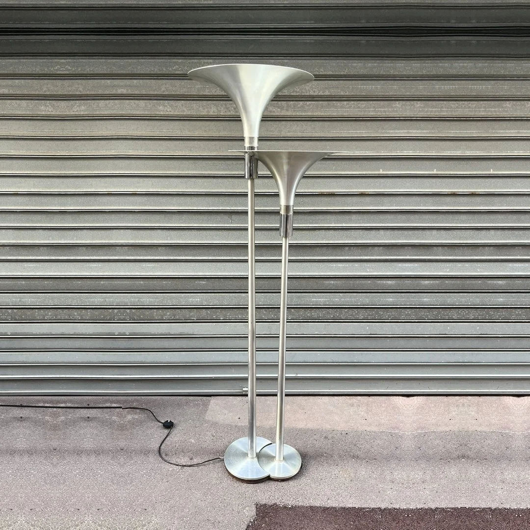 Double lampadaire à vasques en aluminium brossé et chrome devant un rideau de fer, circa 1970