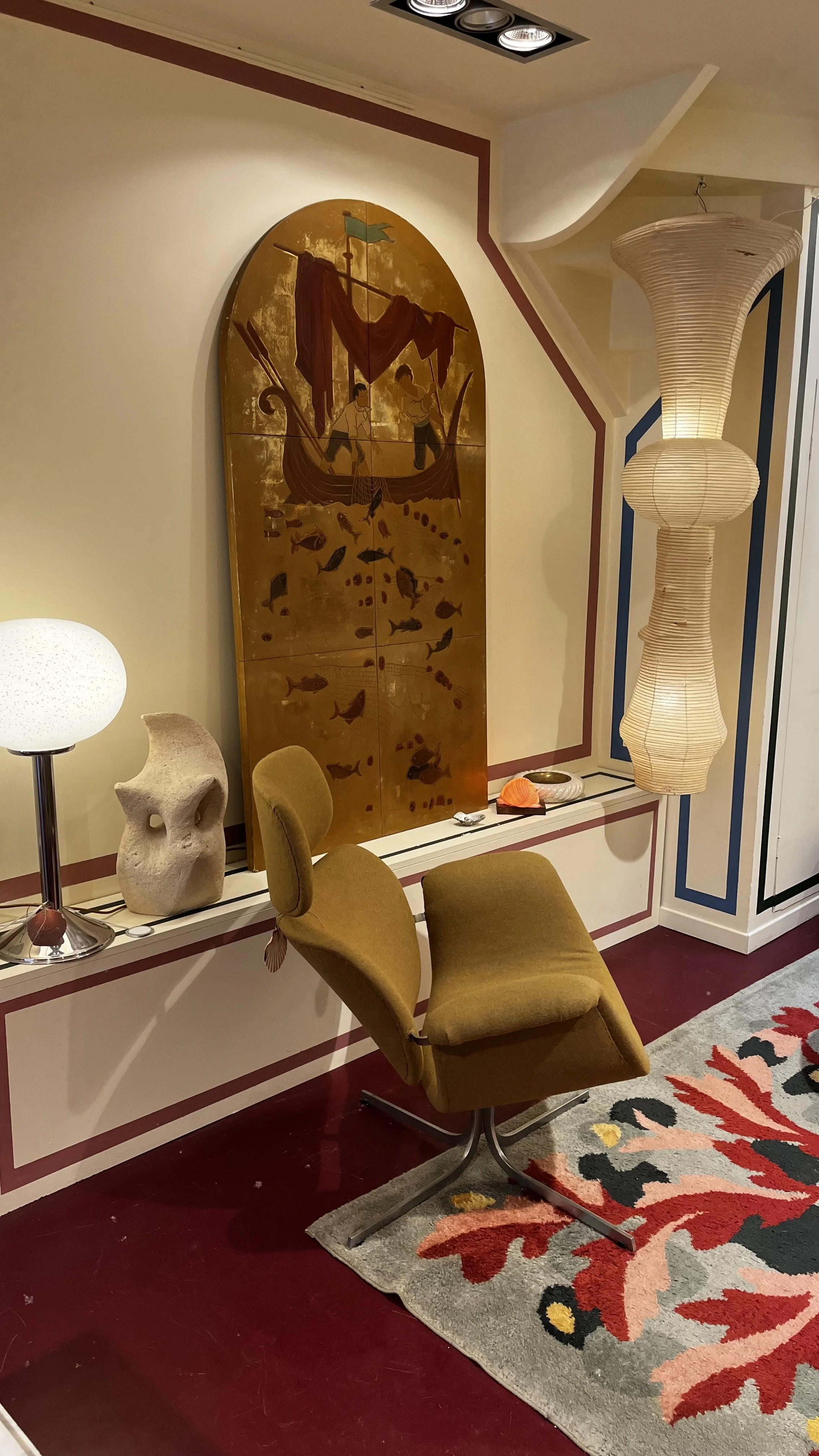 Vue intérieur boutique Ambroise ALLIOU avec un fauteuil de Pierre Paulin, une suspension d'Isamu Noguchi, et un tableau de pêcheurs des années 60