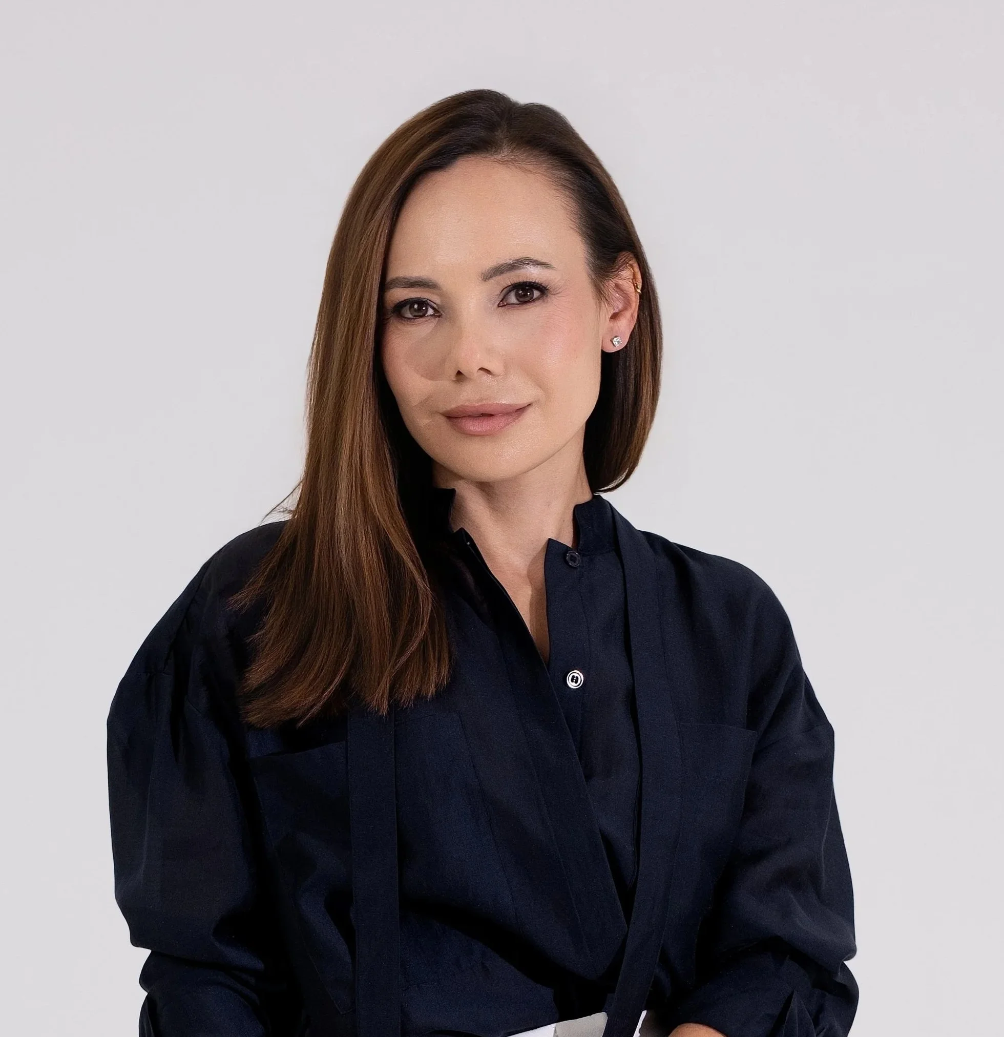 Professional woman with long brown hair wearing a dark navy uniform against a light gray background