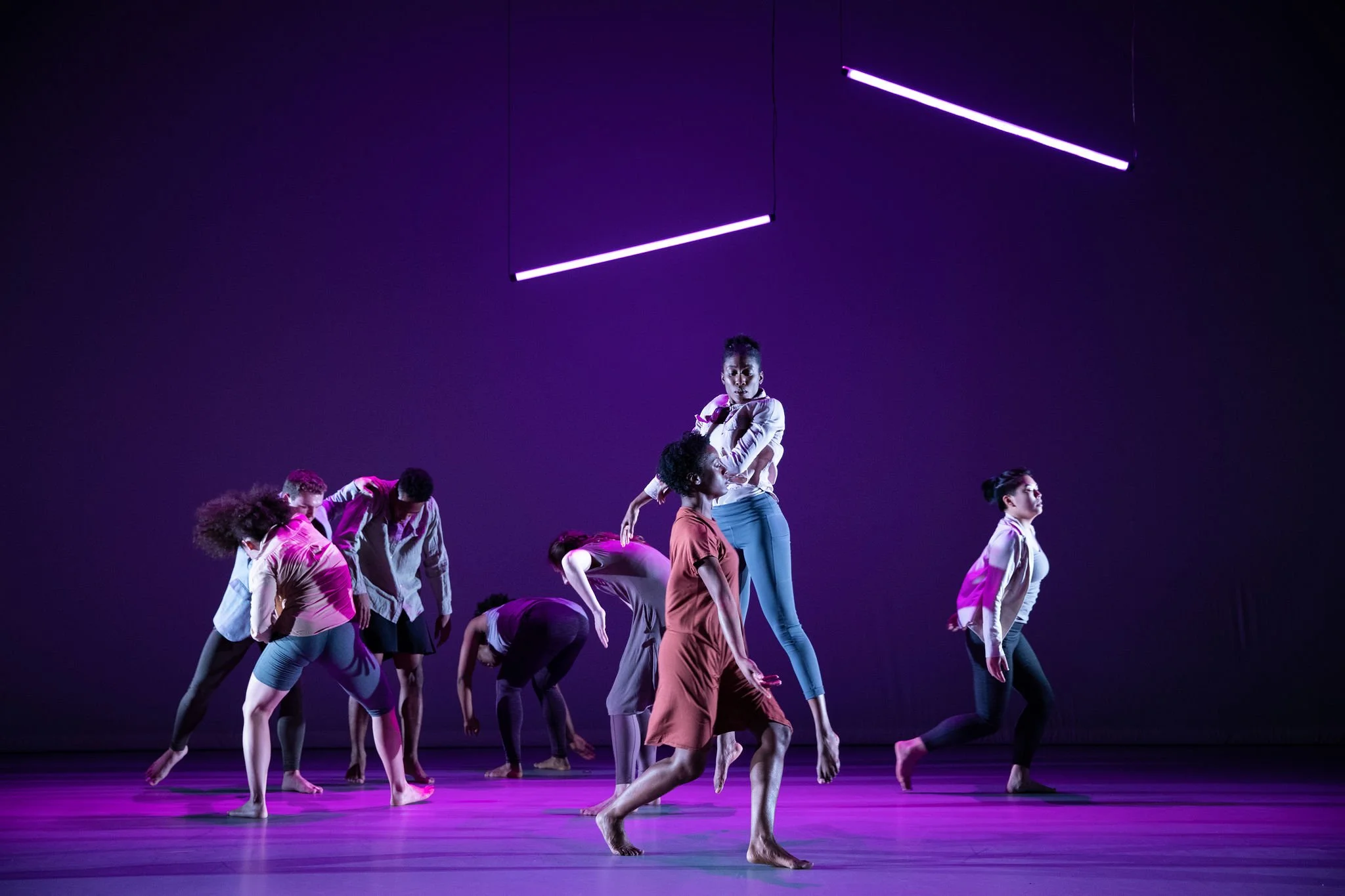 Magenta Production Photo: A group of dancers in movement covered in tones of purple, blue, and magenta.
