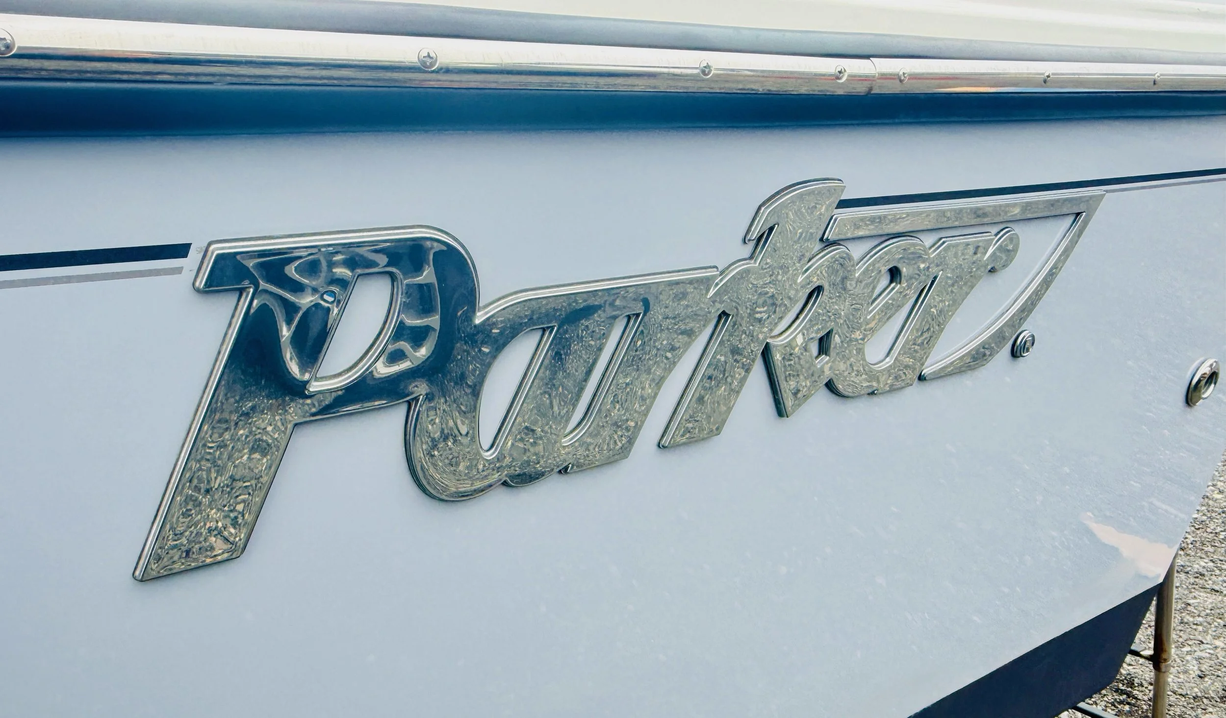 Close-up of a chrome emblem spelling 'Thunderbird' on the side of a white vintage car.