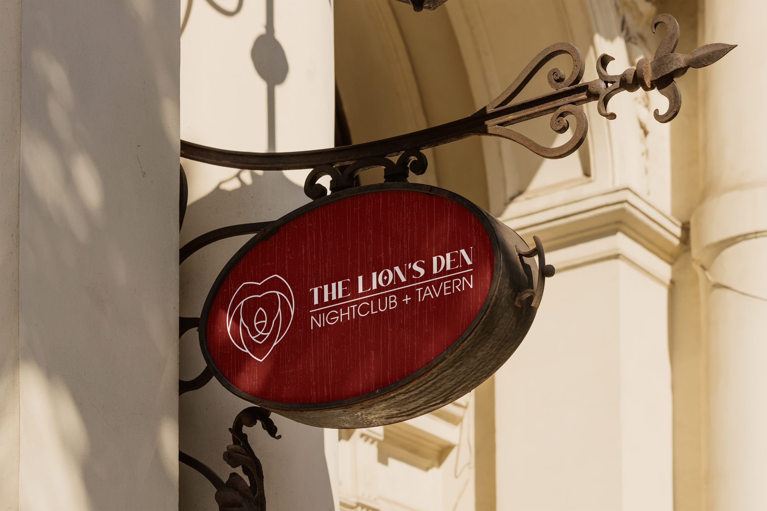 A metal sign for The Lion's Den nightclub and tavern, mounted on an ornate wrought iron bracket on a building exterior with architectural details.