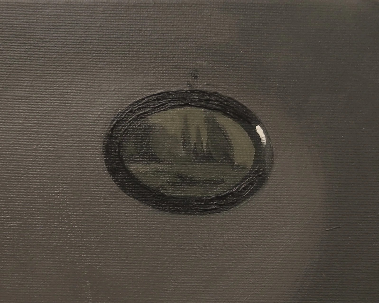 Close-up of a circular glass object with a smiley face design inside, embedded in a gray textured surface.