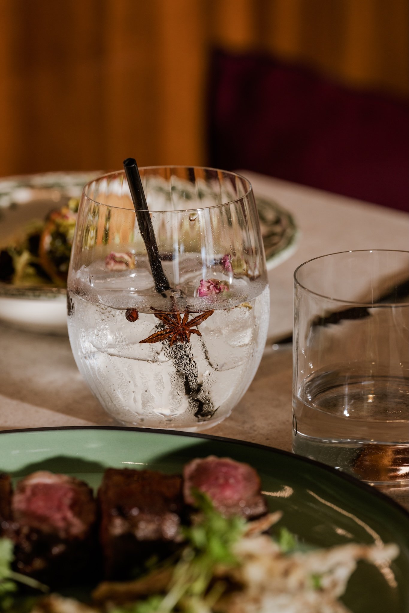 Gin and tonic beside a steak dish, restaurant drinks and food photography Malta