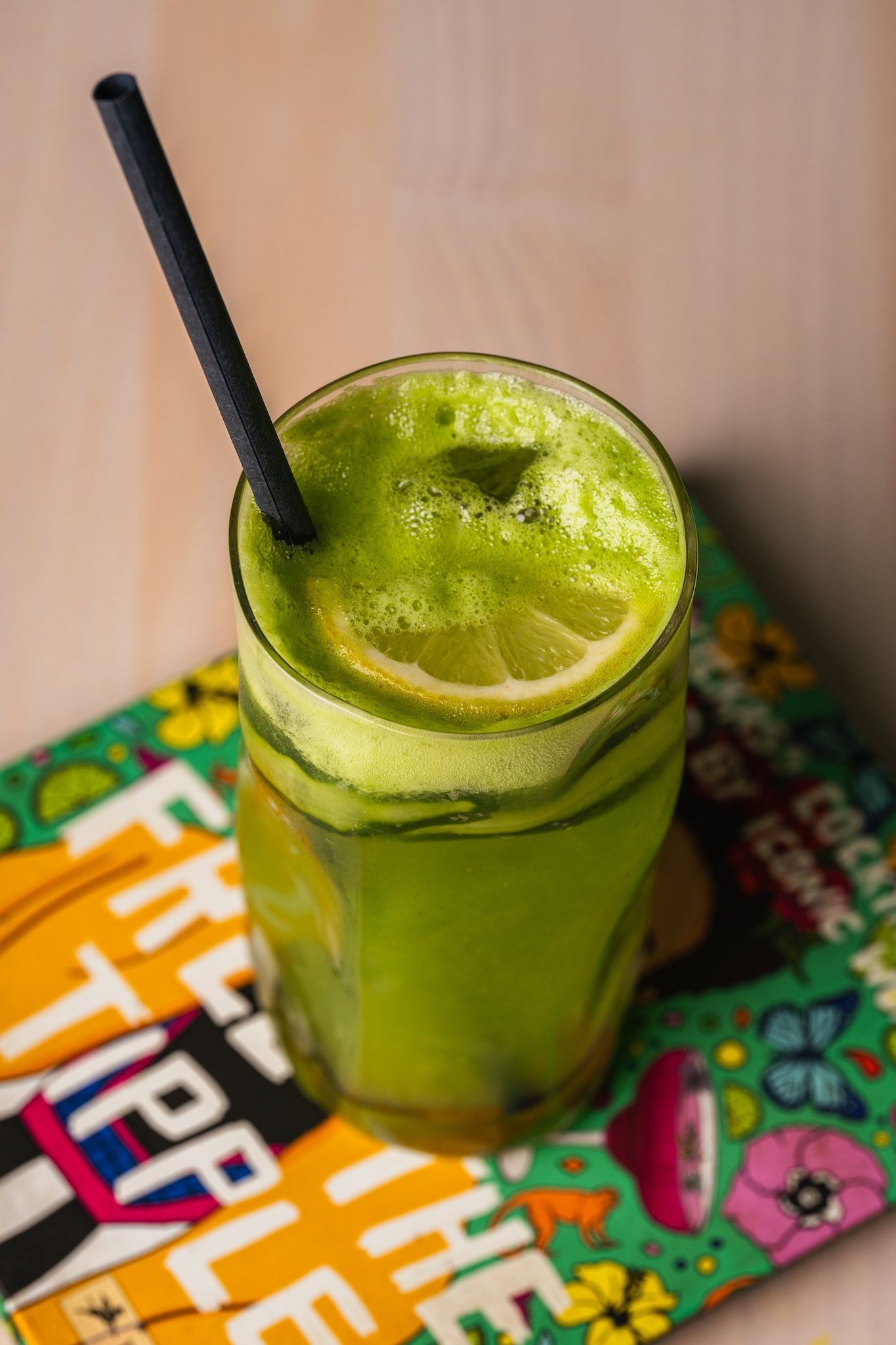 Green smoothie with a lemon slice on a colourful coaster, drinks photography