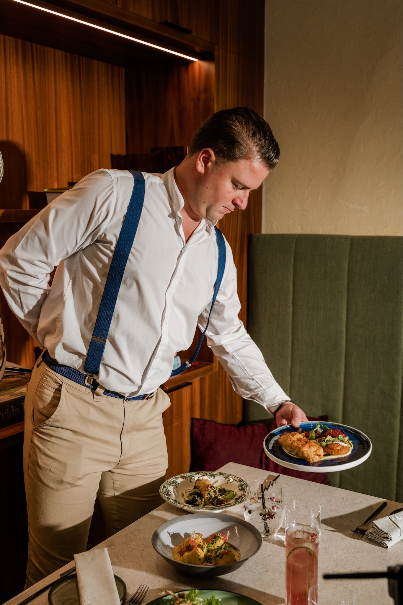 Waiter serving dishes at a restaurant table, hospitality photography Malta