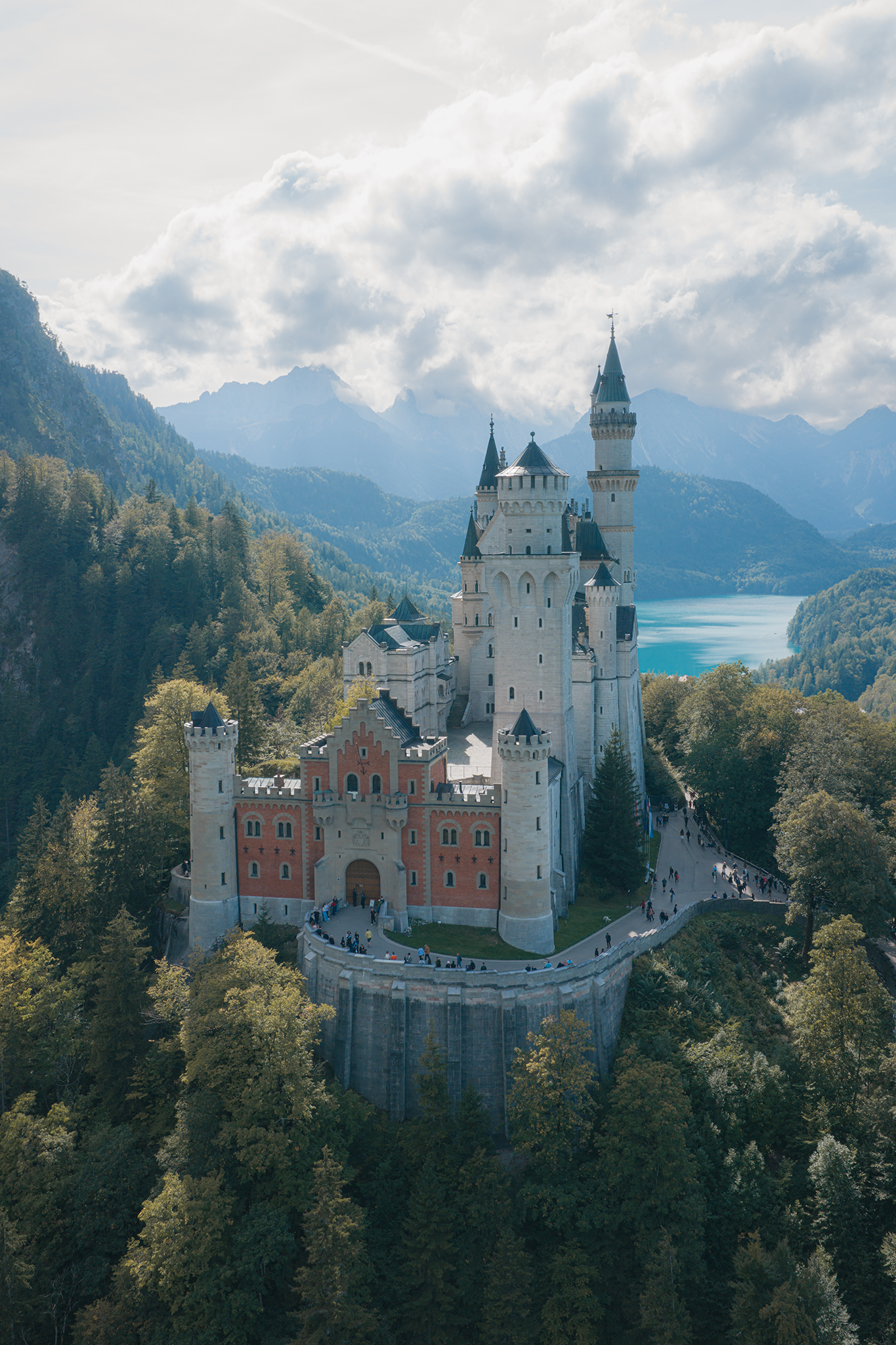 Aerial drone photograph of a hilltop castle surrounded by forest and mountains