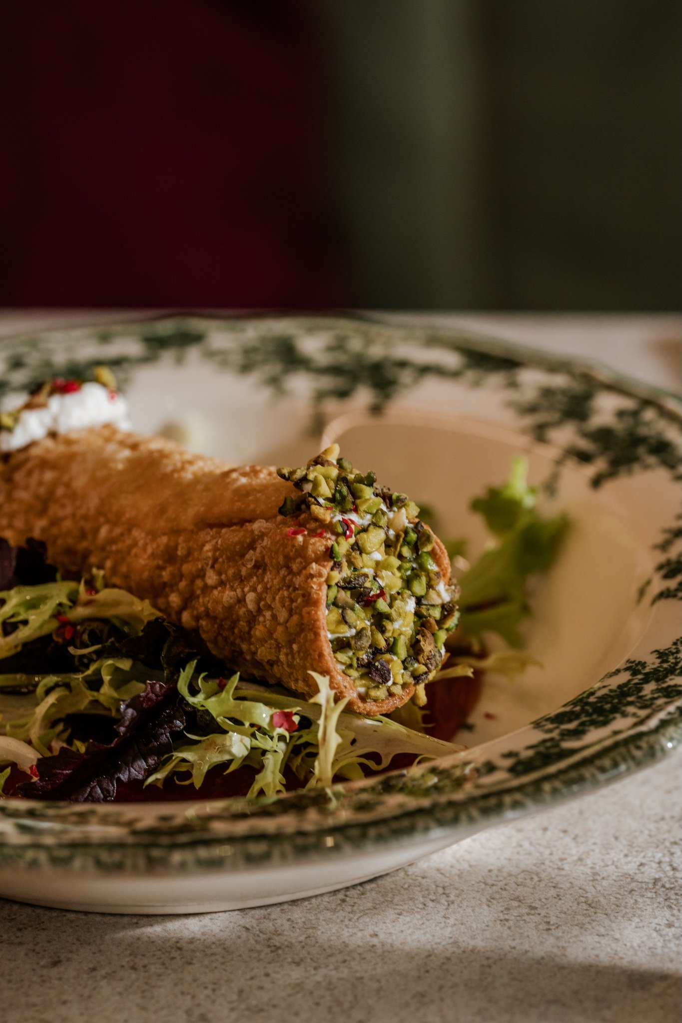 Crispy breaded dish with greens on a patterned plate, food photography