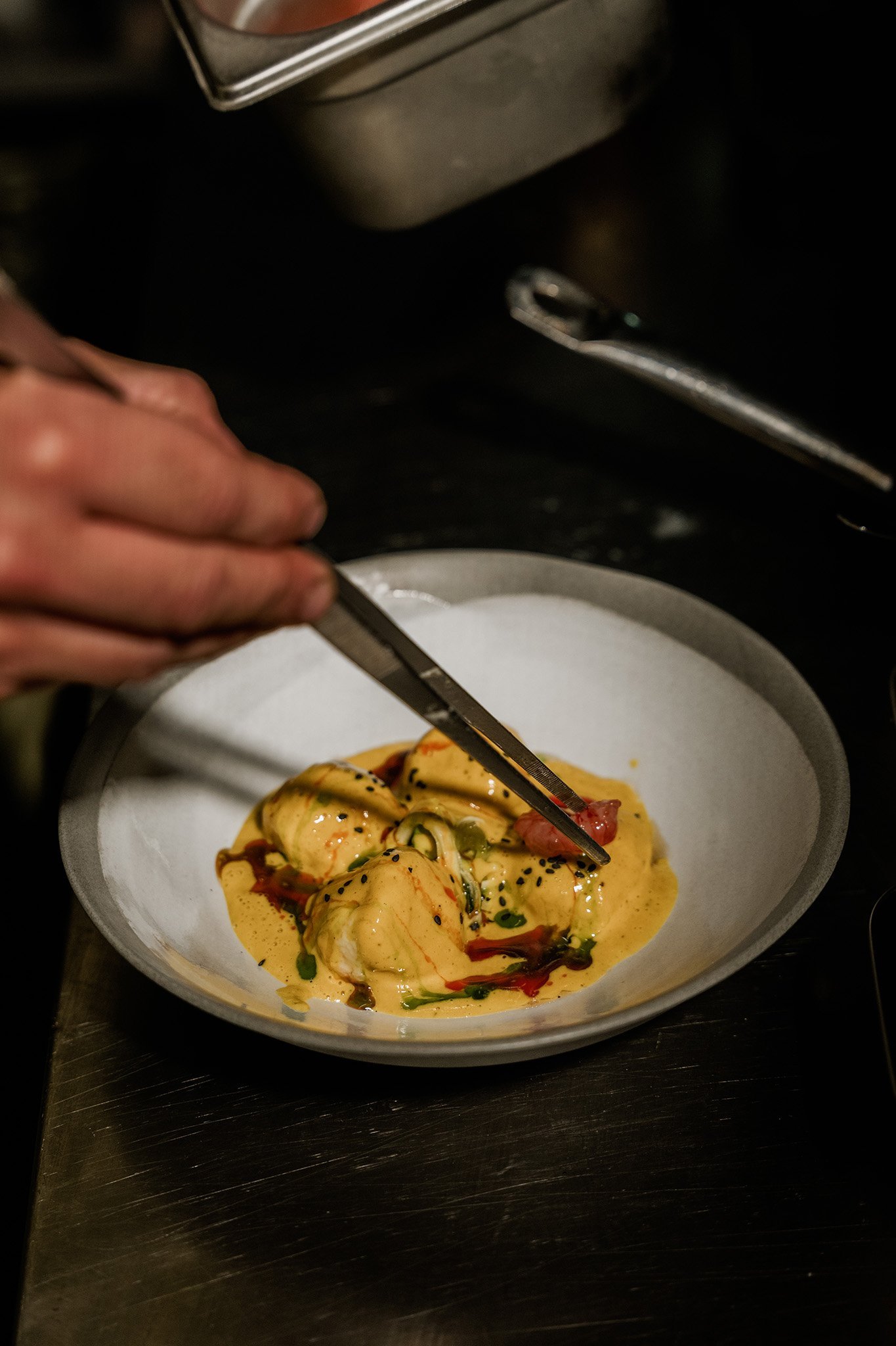 Chef plating ravioli with tweezers, restaurant kitchen photography Malta