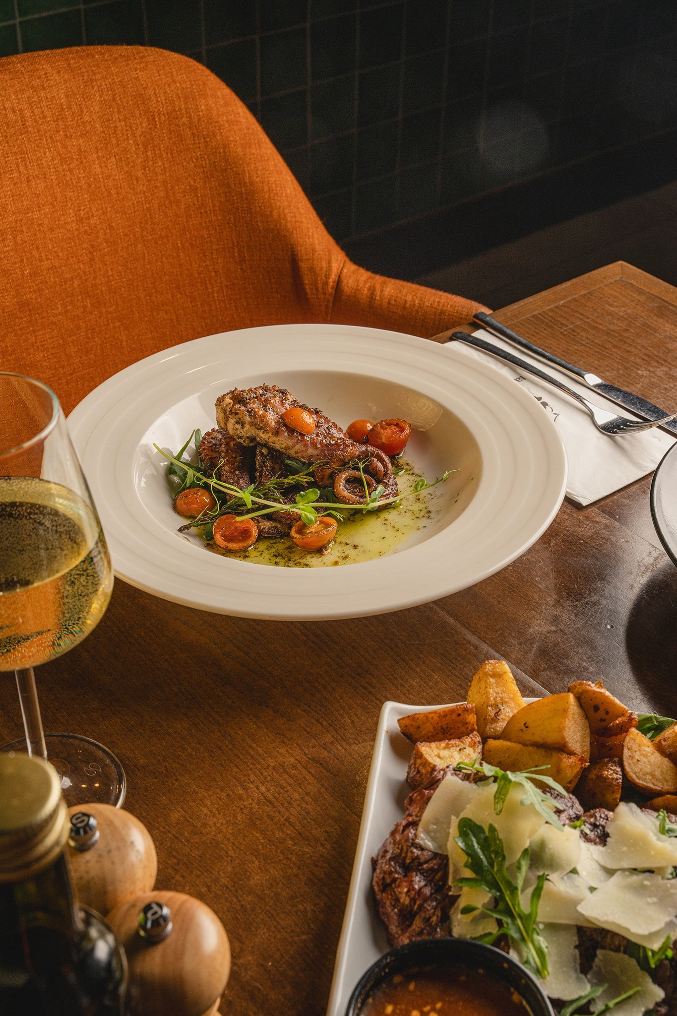 Plated starter on a restaurant table with orange chairs, venue and food photography